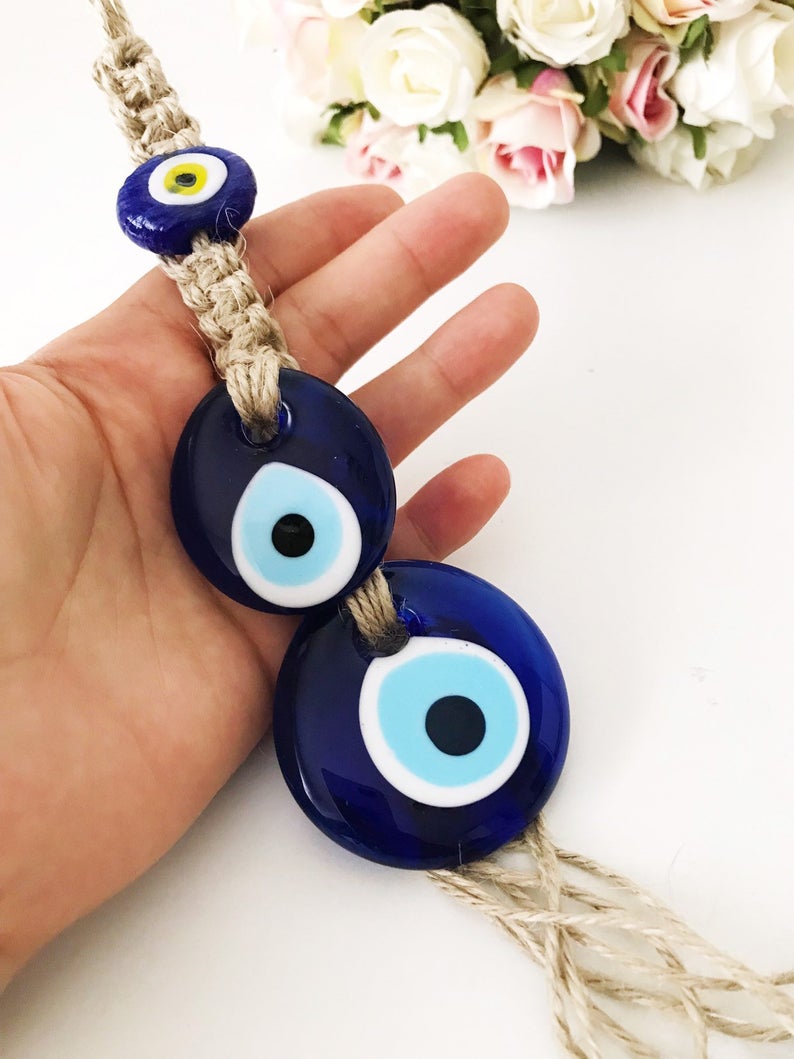 Handmade evil eye protection wall hanging featuring 11 unique blue evil eye beads and macrame design, perfect for home decoration.