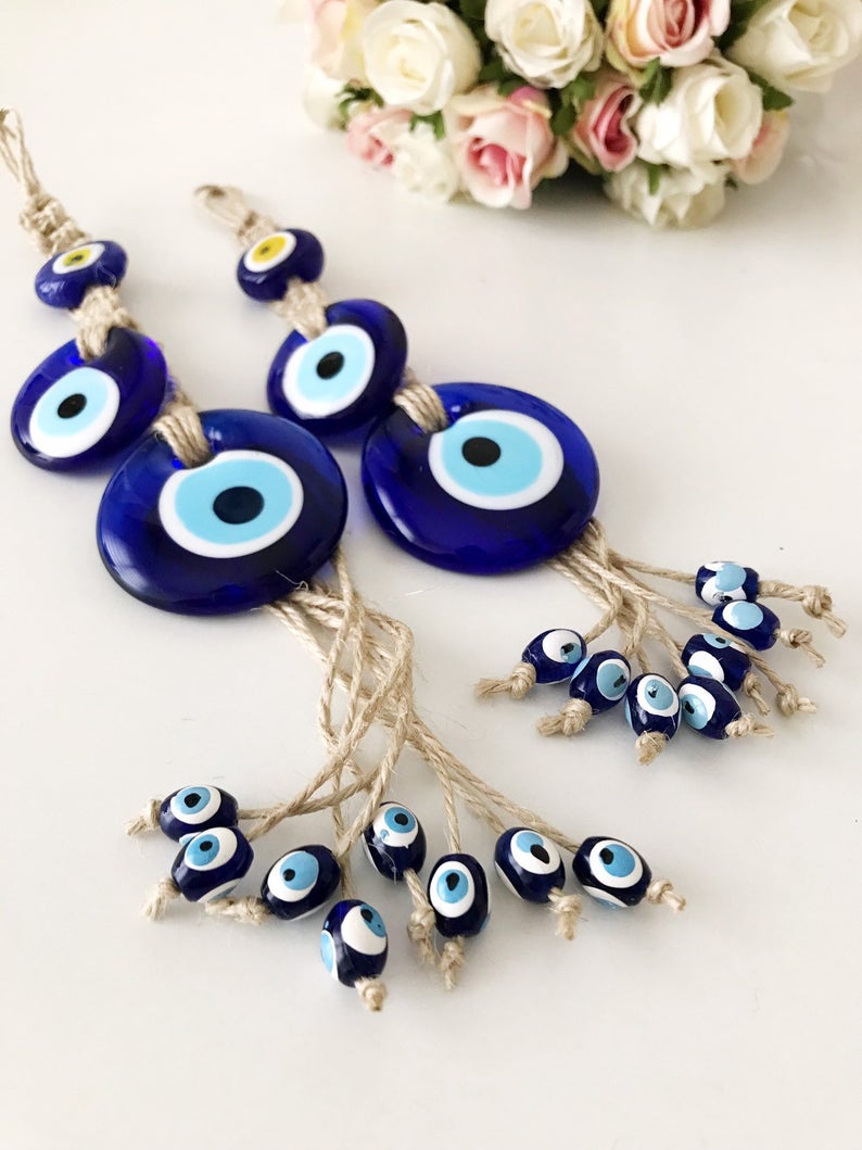 Handmade evil eye protection wall hanging featuring 11 unique blue evil eye beads and macrame design, perfect for home decoration.