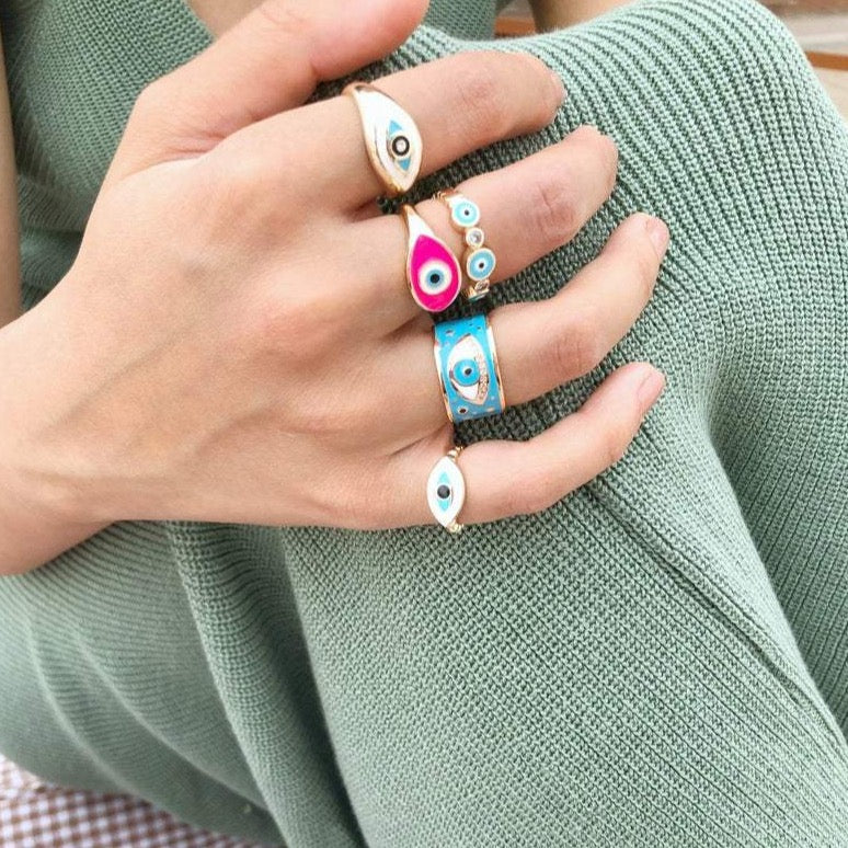 Adjustable gold evil eye ring featuring an oval design with a blue, white, or pink evil eye bead, symbolizing protection and style.
