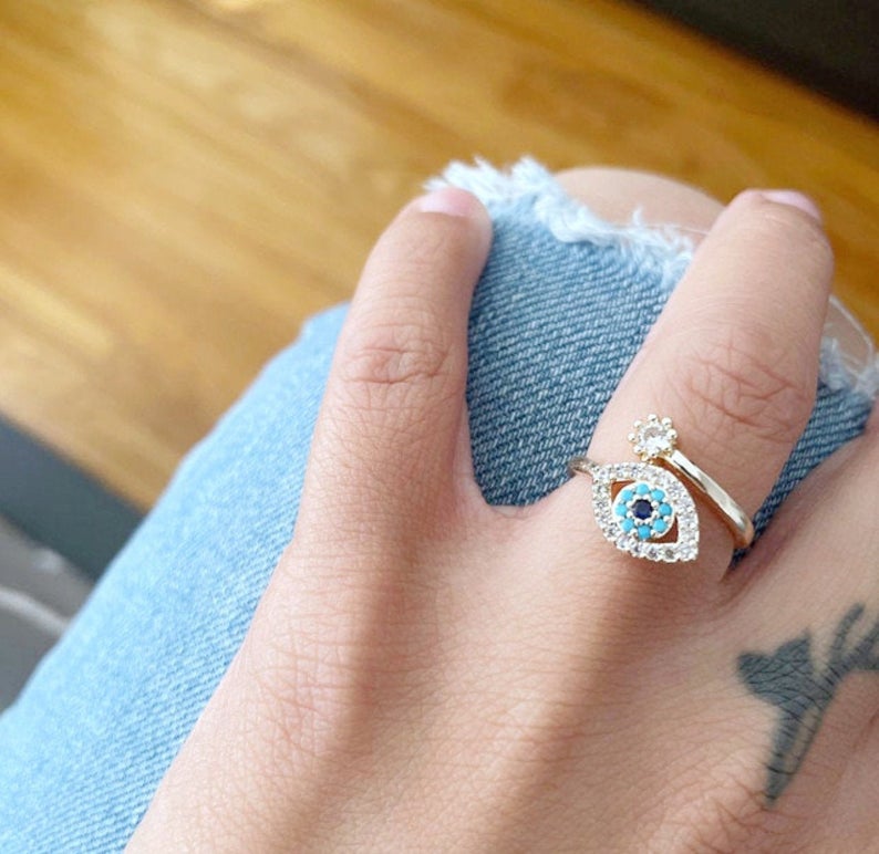 Evil Eye Ring featuring a blue eye design, available in gold, silver, and rose gold, adorned with zircon charms.
