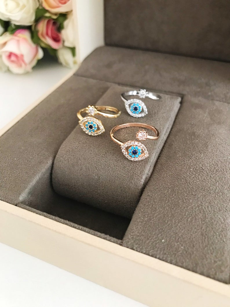 Evil Eye Ring featuring a blue eye design, available in gold, silver, and rose gold, adorned with zircon charms.