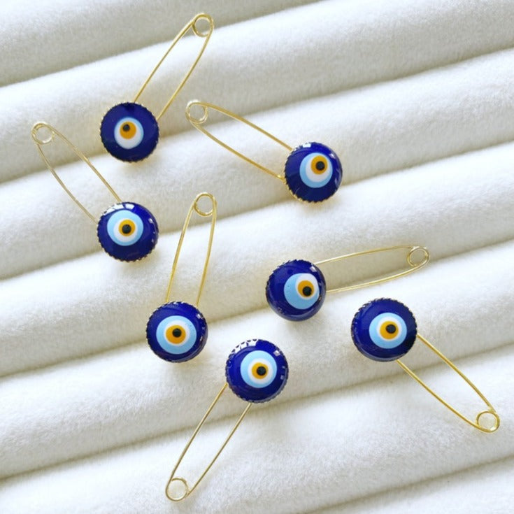 A tiny blue evil eye safety pin made of brass, featuring an 8mm evil eye bead, designed for baby protection and special occasions.