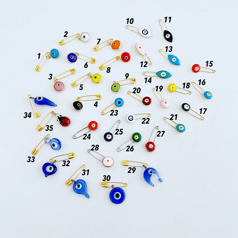 A collection of brass evil eye safety pins in various styles, showcasing their unique charm and design.