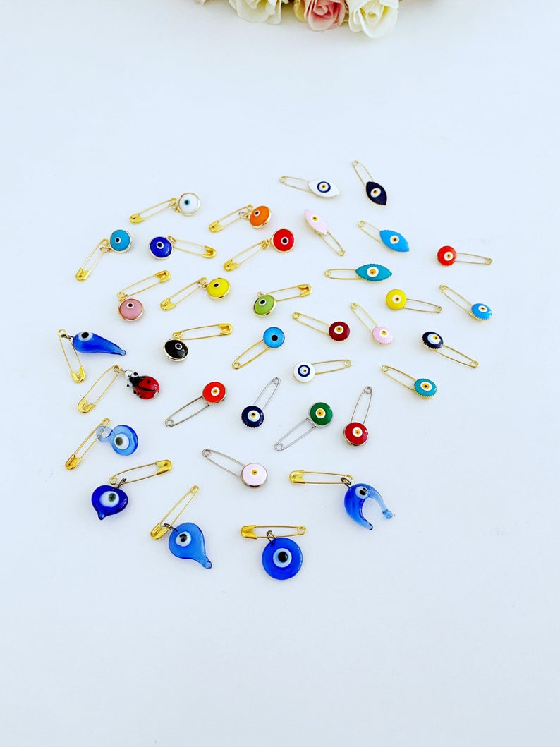 A collection of brass evil eye safety pins in various styles, showcasing their unique charm and design.