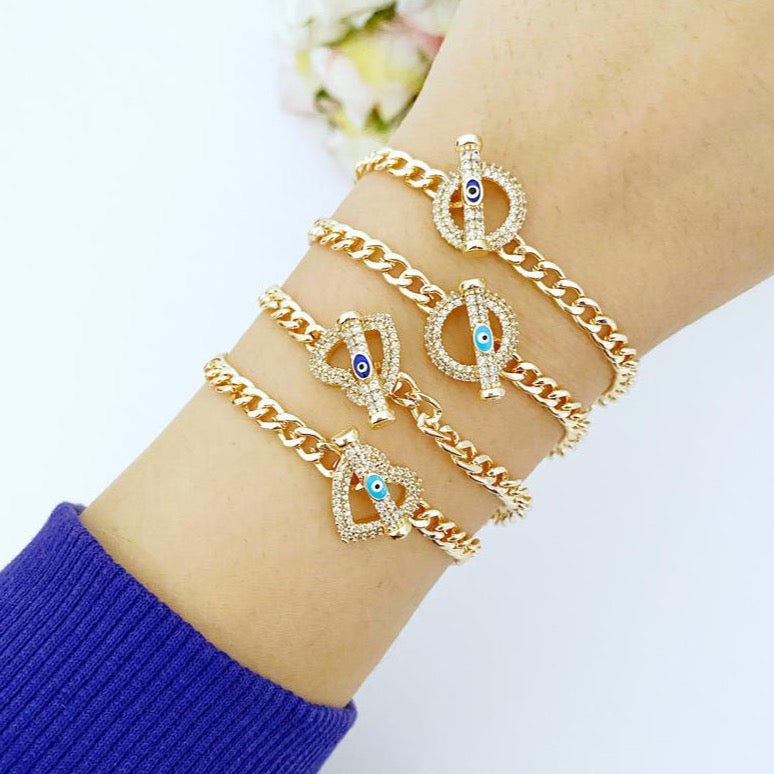 Evil Eye Toggle Bracelet featuring a gold chain, heart charm, and customizable evil eye colors, showcasing its elegant design and handmade quality.