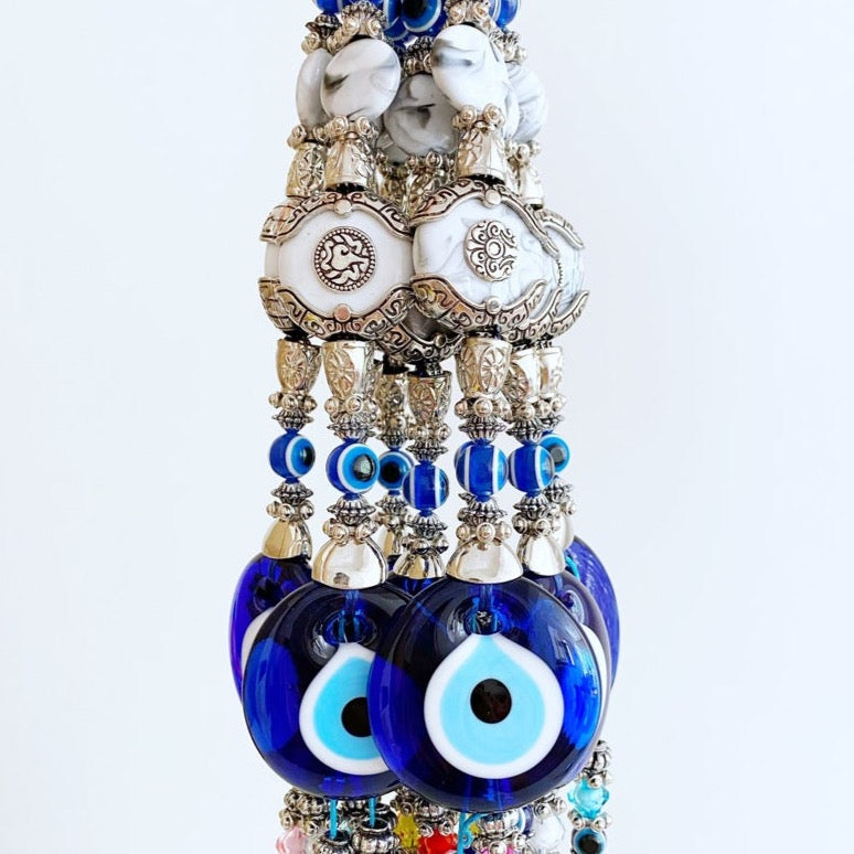 Evil Eye Wall Decor featuring a creamy charm design with a blue glass evil eye bead and turquoise charm, perfect for home protection.