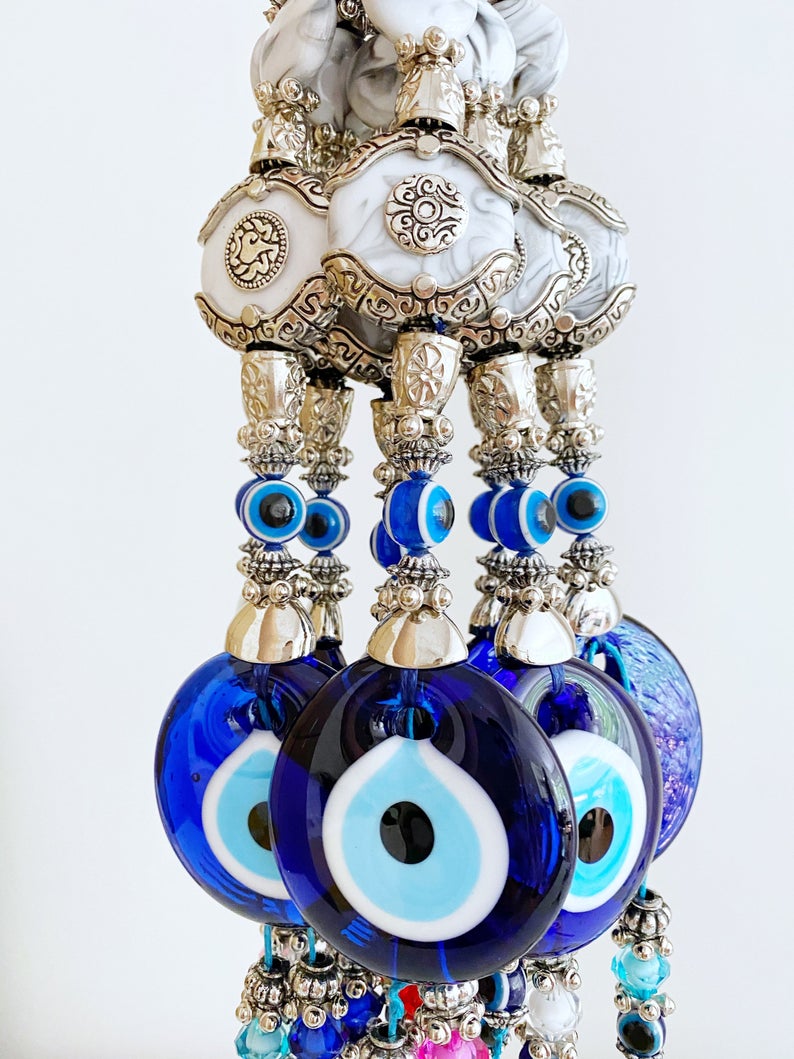 Evil Eye Wall Decor featuring a creamy charm design with a blue glass evil eye bead and turquoise charm, perfect for home protection.