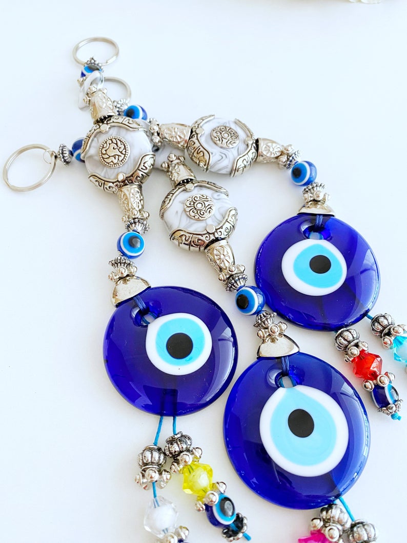 Evil Eye Wall Decor featuring a creamy charm design with a blue glass evil eye bead and turquoise charm, perfect for home protection.