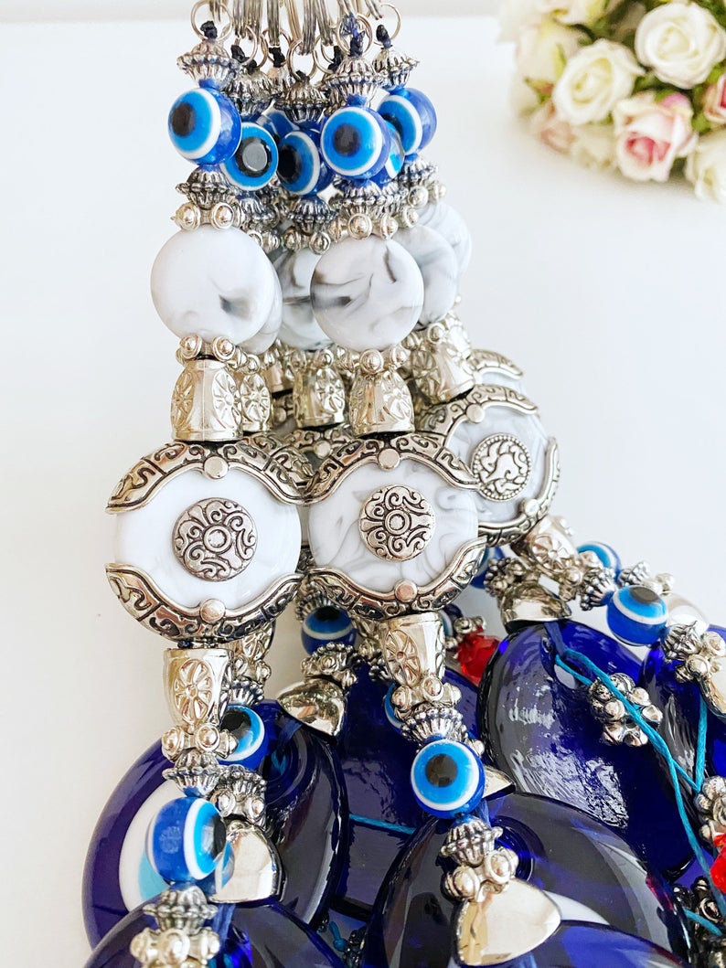 Evil Eye Wall Decor featuring a creamy charm design with a blue glass evil eye bead and turquoise charm, perfect for home protection.