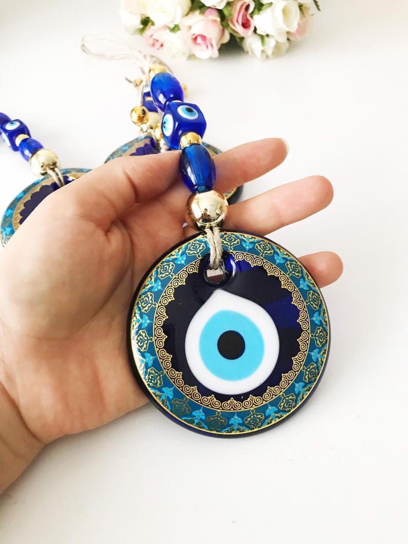 A beautiful blue evil eye wall hanging featuring glass beads, symbolizing protection and good luck, perfect for home decor.