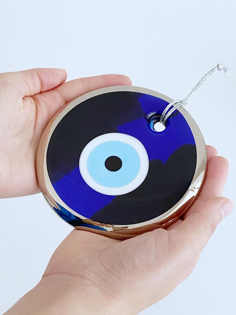 A beautiful blue evil eye wall hanging featuring glass beads, symbolizing protection and good luck, perfect for home decor.