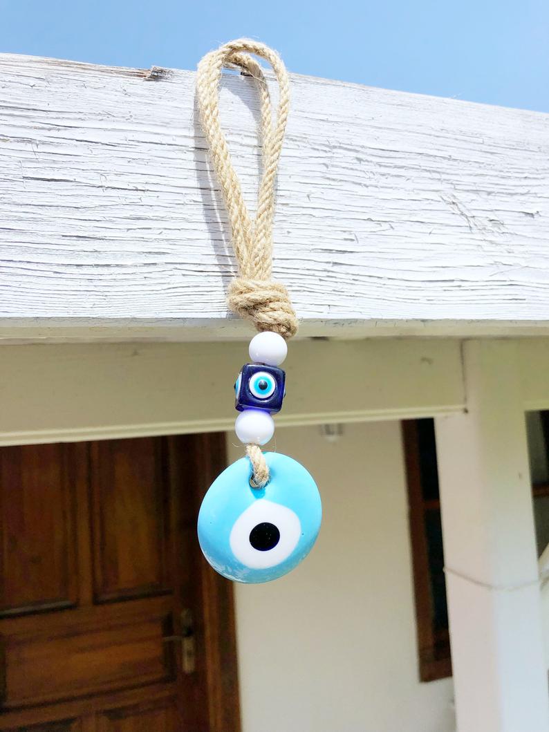 A beautiful blue evil eye wall hanging featuring glass beads, symbolizing protection and good luck, perfect for home decor.