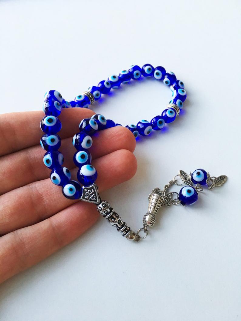 A beautiful blue evil eye wall hanging featuring glass beads, symbolizing protection and good luck, perfect for home decor.
