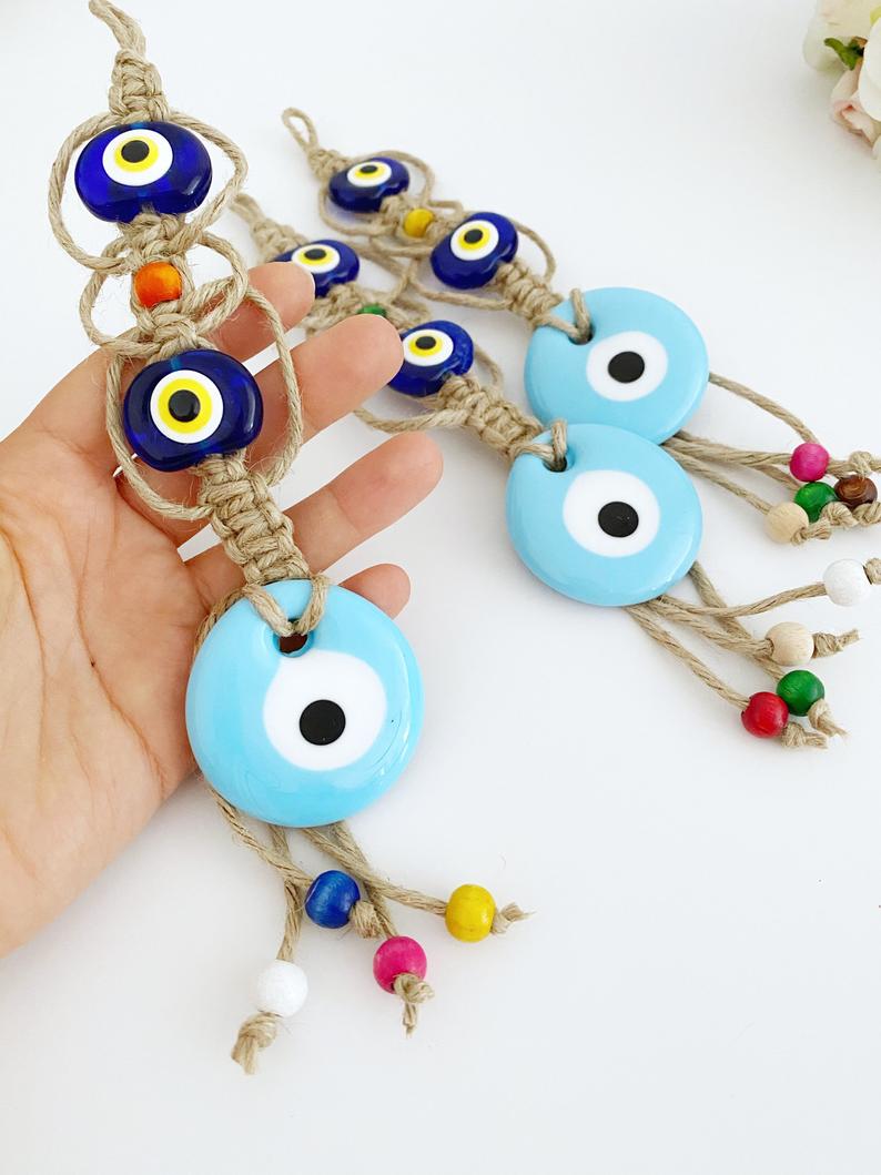 Handmade Evil Eye Wall Hanging featuring a large blue evil eye bead and macrame design, symbolizing protection and good luck.