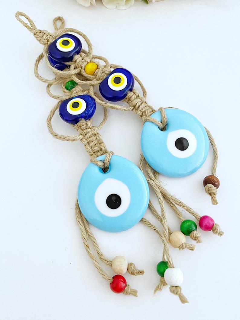 Handmade Evil Eye Wall Hanging featuring a large blue evil eye bead and macrame design, symbolizing protection and good luck.