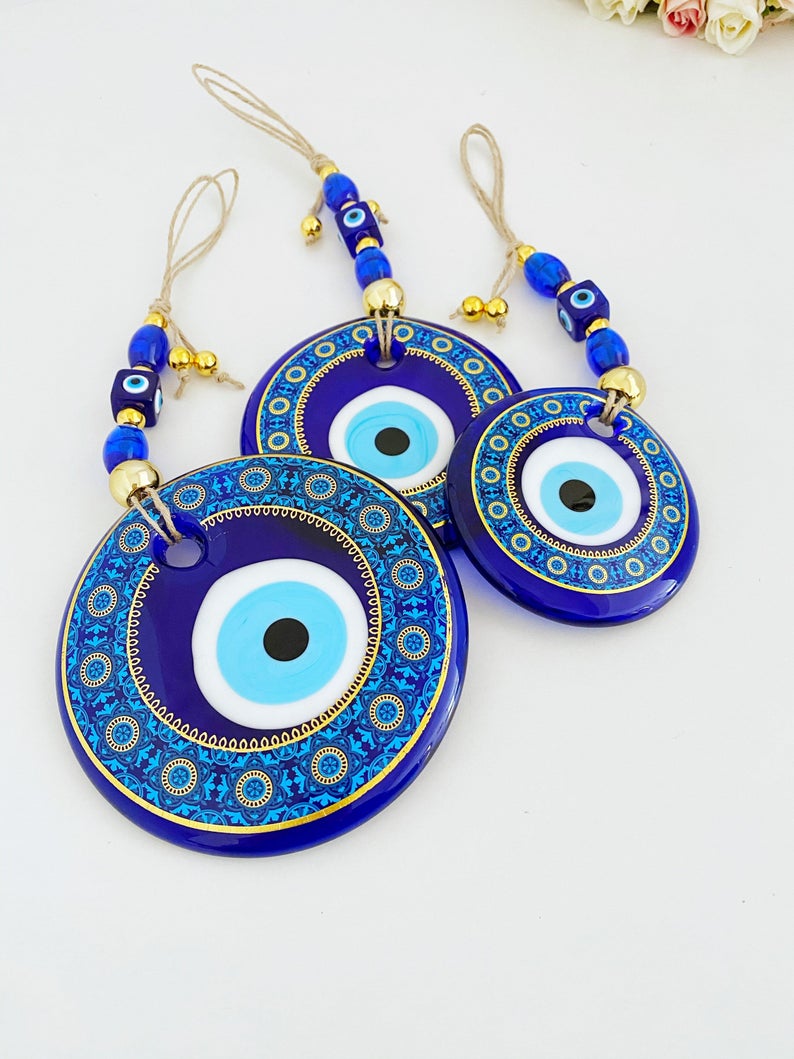 A beautifully crafted Evil Eye Wall Hanging featuring a vibrant blue evil eye bead and intricate patterns, perfect for home decor.