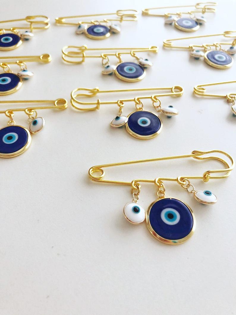 Evil Eye Wedding Favor featuring a blue Murano bead and gold plated safety pin, adorned with white glass evil eye beads.