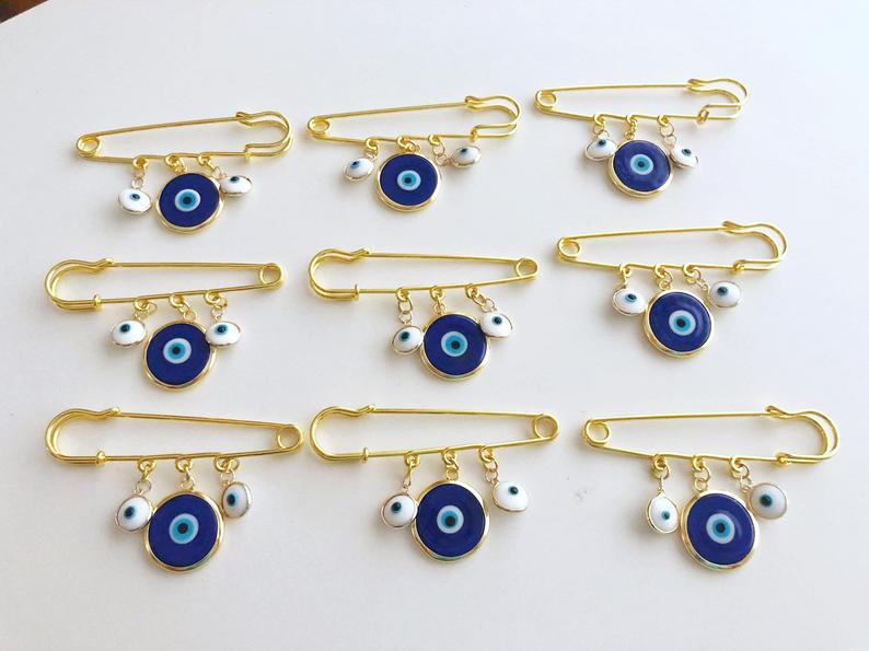 Evil Eye Wedding Favor featuring a blue Murano bead and gold plated safety pin, adorned with white glass evil eye beads.