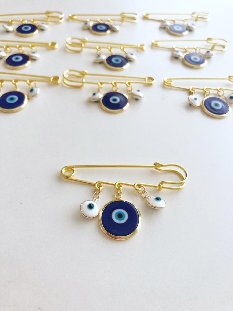 Evil Eye Wedding Favor featuring a blue Murano bead and gold plated safety pin, adorned with white glass evil eye beads.