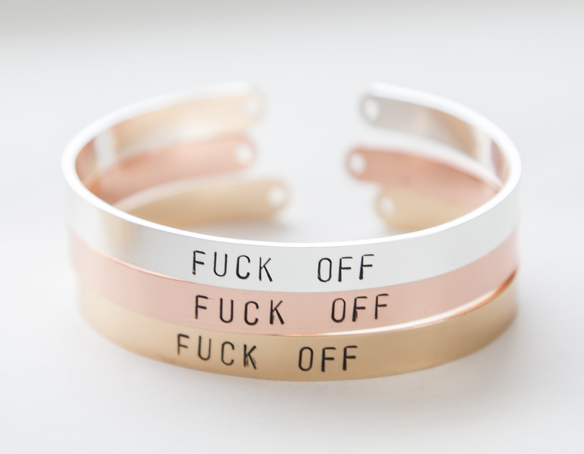 A hand-stamped gold plated cuff bracelet with the phrase 'F off', showcasing its unique design and adjustable size.