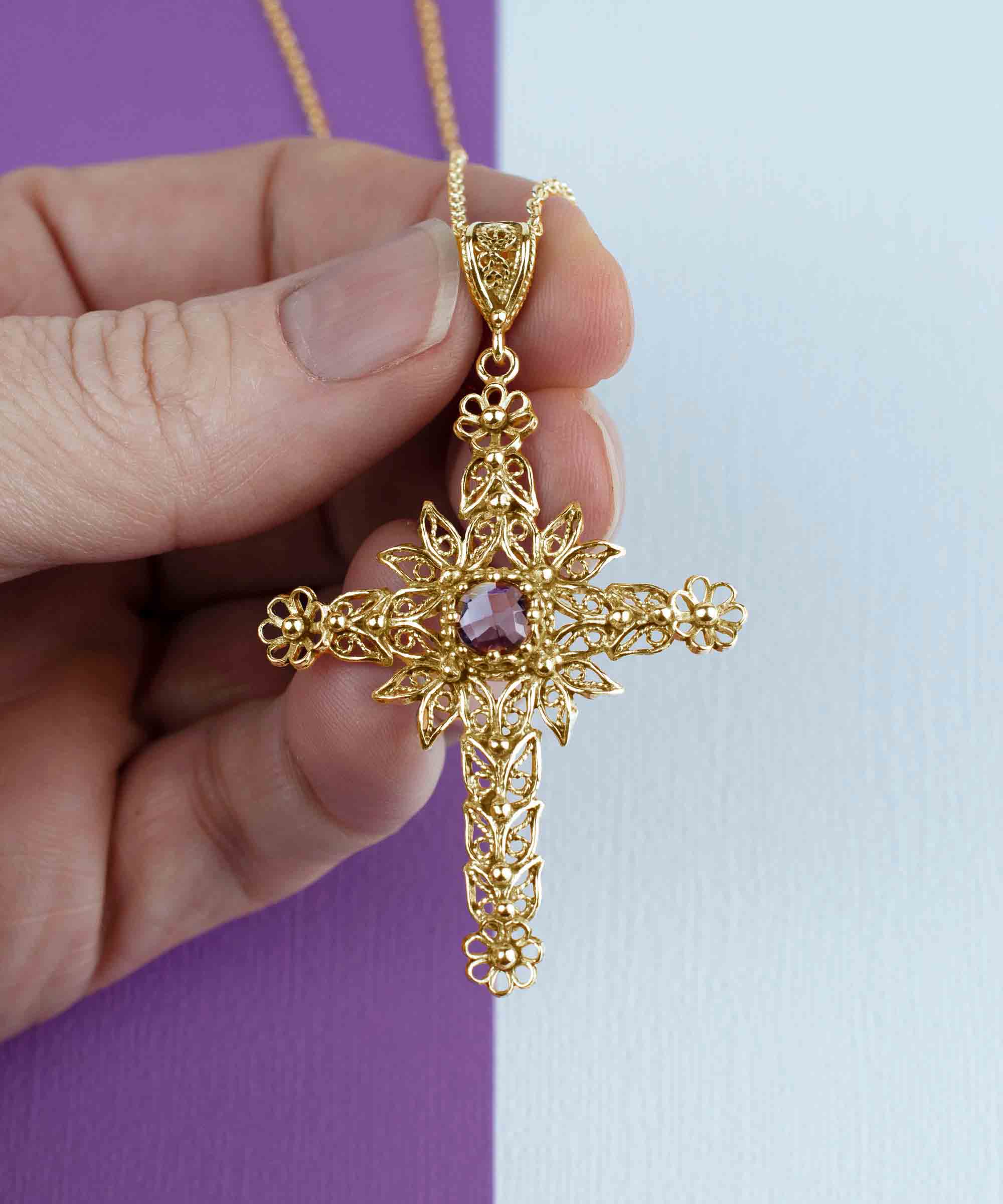 Gold plated silver cross pendant featuring intricate filigree art and a beautiful Amethyst gemstone, perfect for women.