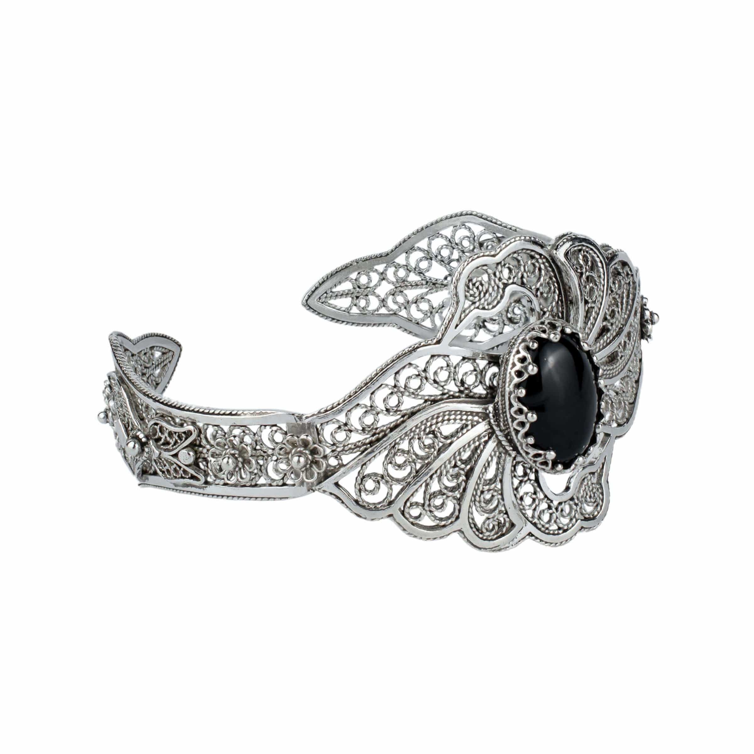 Sterling silver cuff bracelet featuring filigree art and a black onyx gemstone in a double swan design.