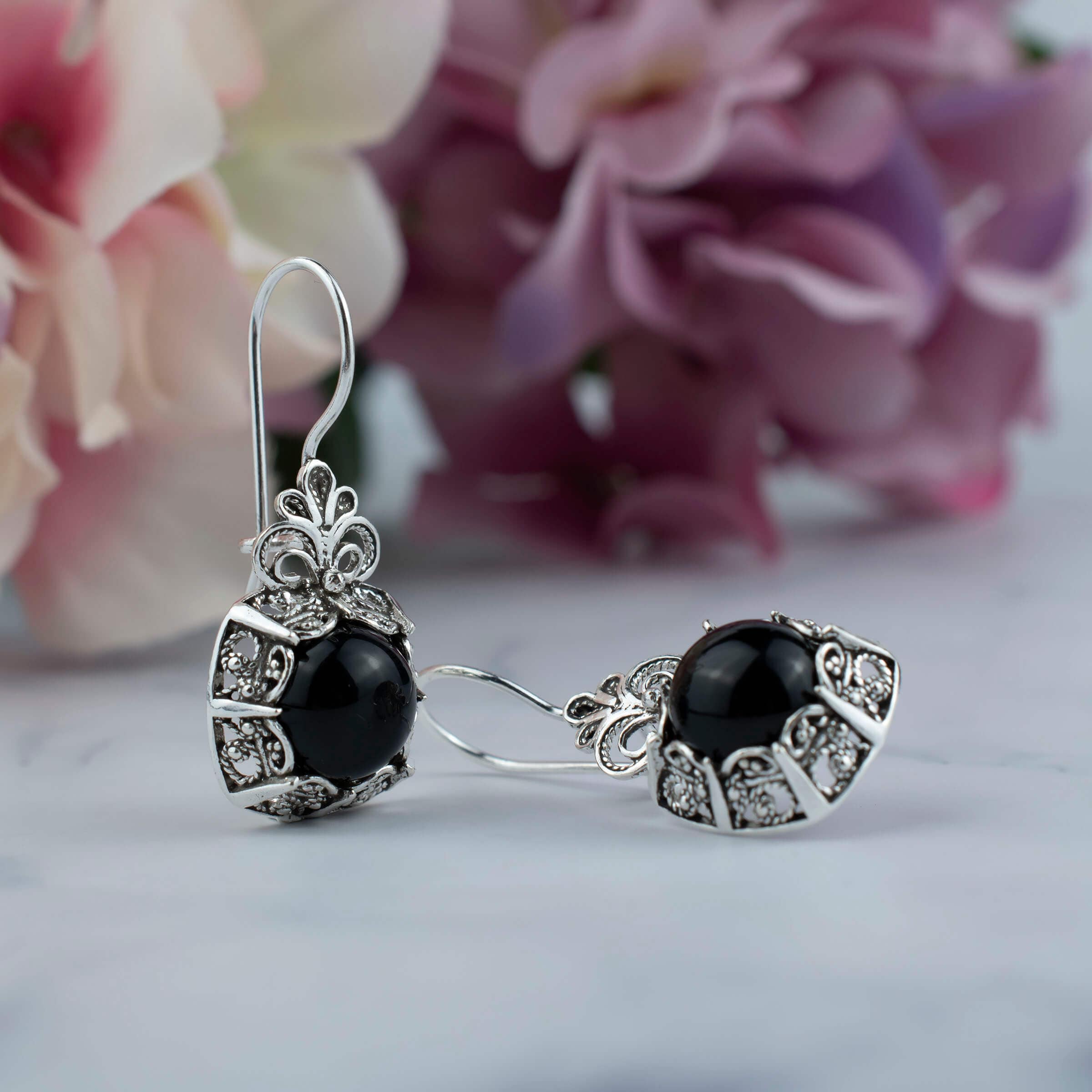 Elegant handmade silver drop earrings featuring intricate filigree design and black onyx gemstone.