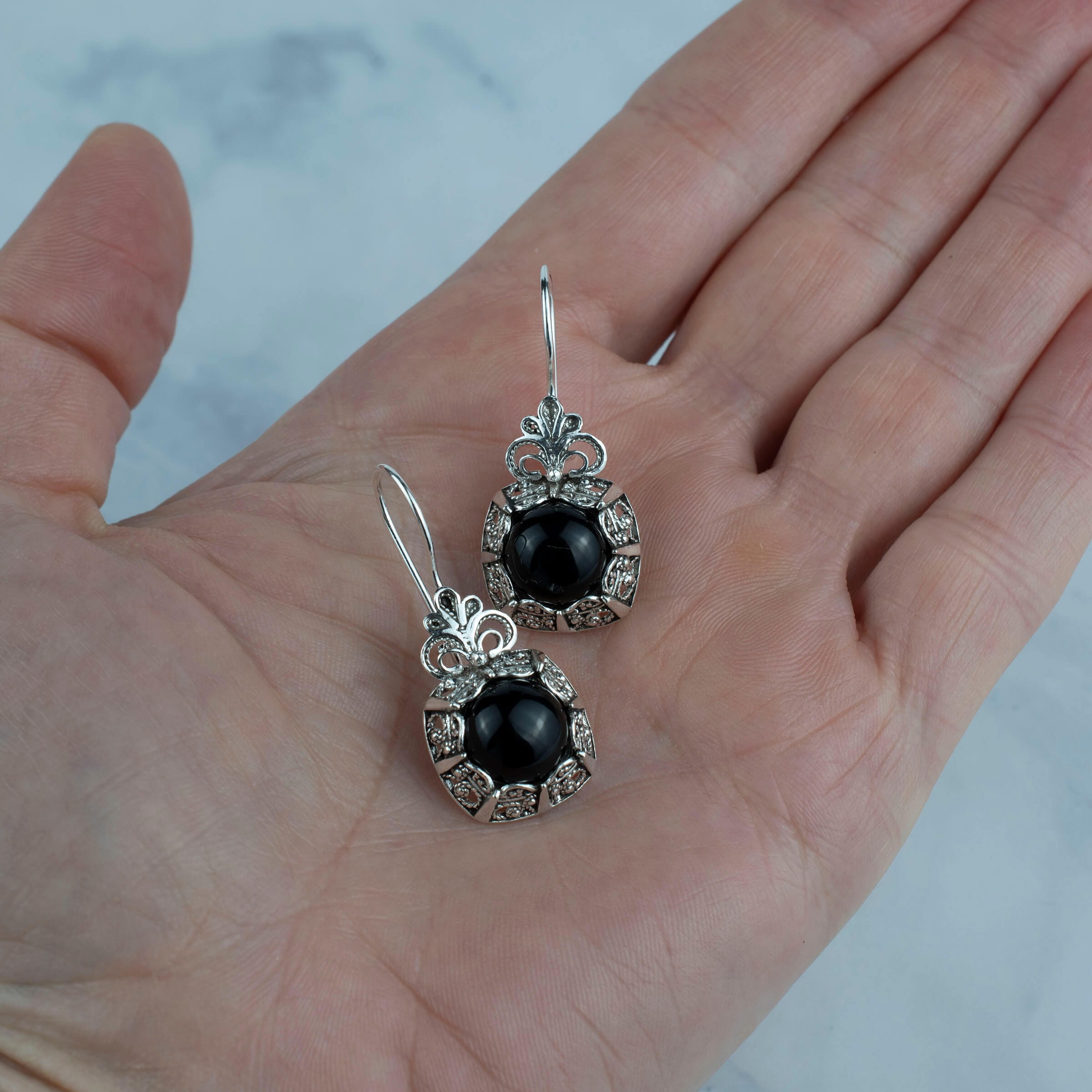 Elegant handmade silver drop earrings featuring intricate filigree design and black onyx gemstone.
