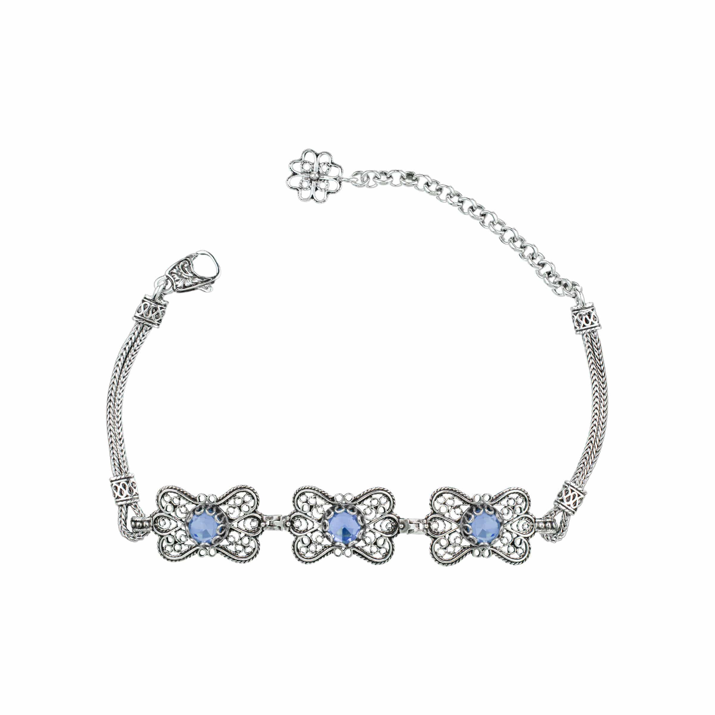 A stunning sterling silver bracelet featuring filigree art and a blue quartz gemstone in a butterfly design, elegantly displayed on a soft surface.