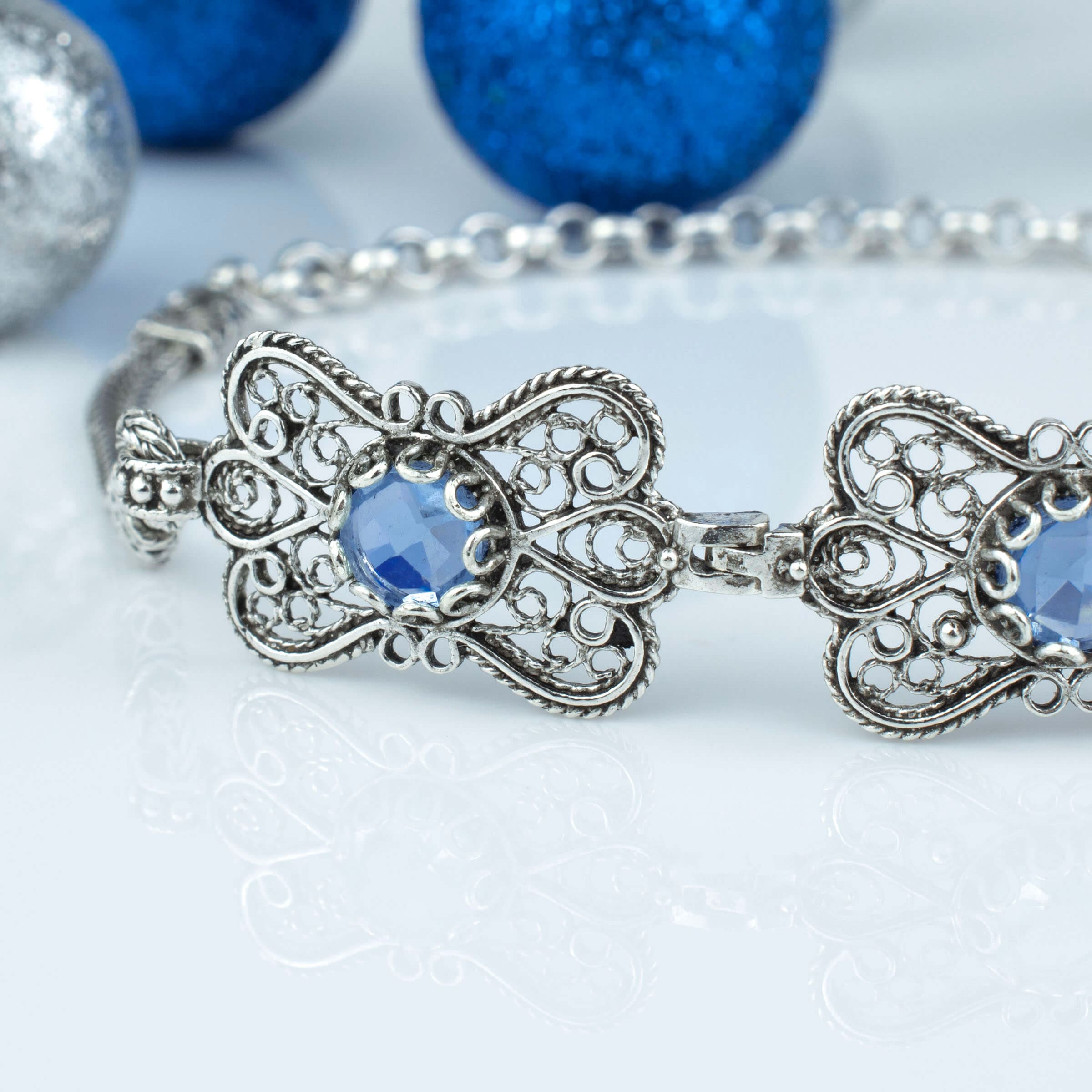 A stunning sterling silver bracelet featuring filigree art and a blue quartz gemstone in a butterfly design, elegantly displayed on a soft surface.