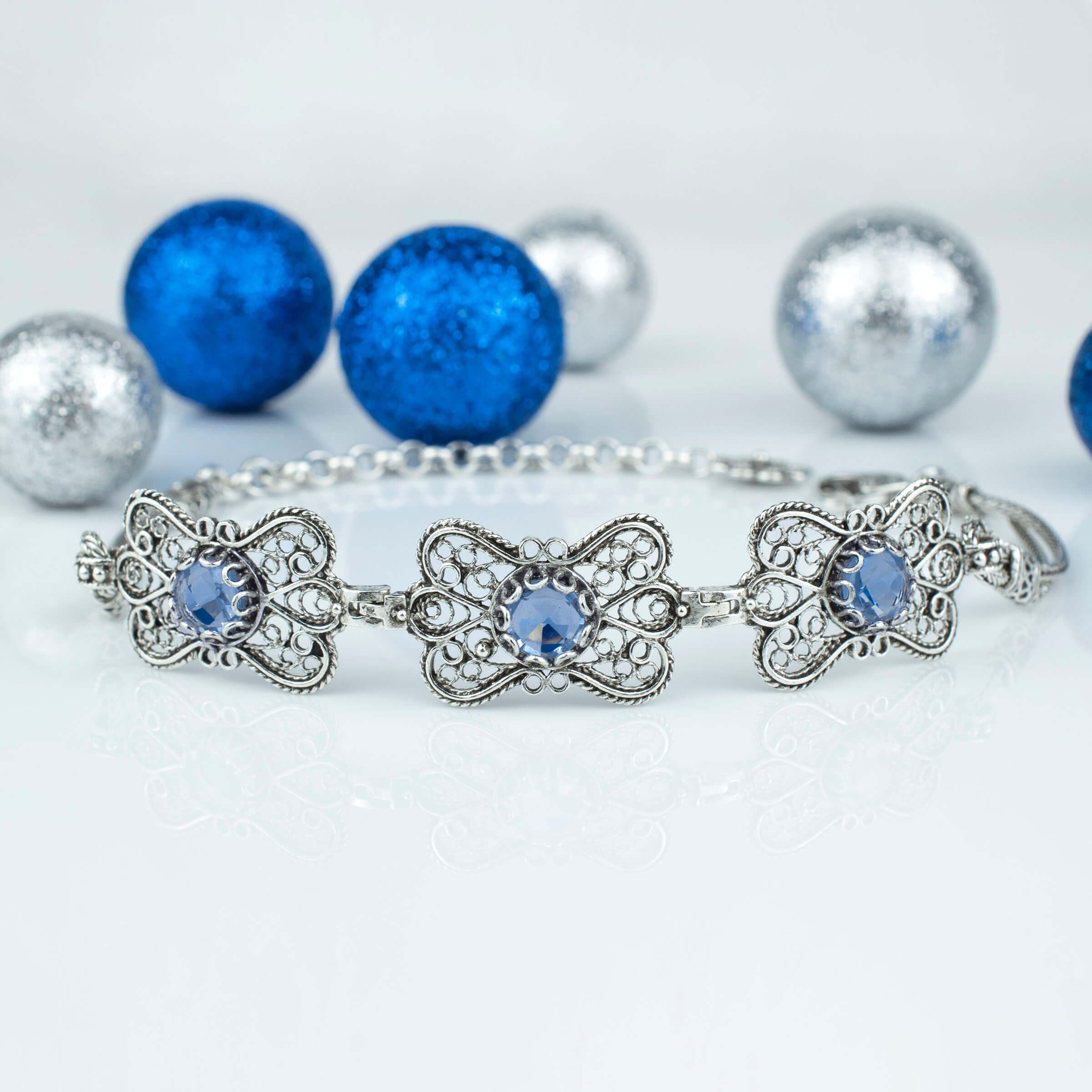 A stunning sterling silver bracelet featuring filigree art and a blue quartz gemstone in a butterfly design, elegantly displayed on a soft surface.