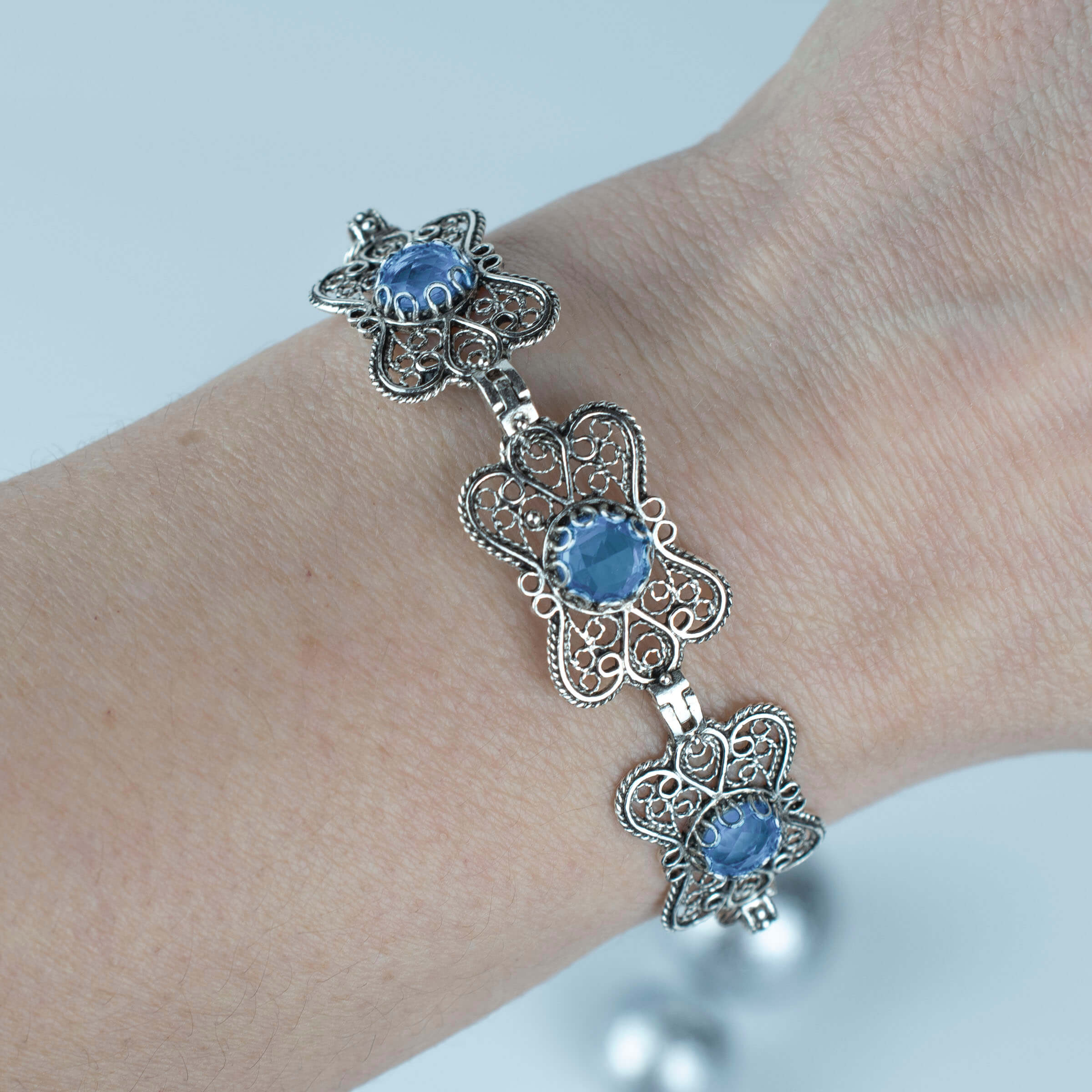 A stunning sterling silver bracelet featuring filigree art and a blue quartz gemstone in a butterfly design, elegantly displayed on a soft surface.