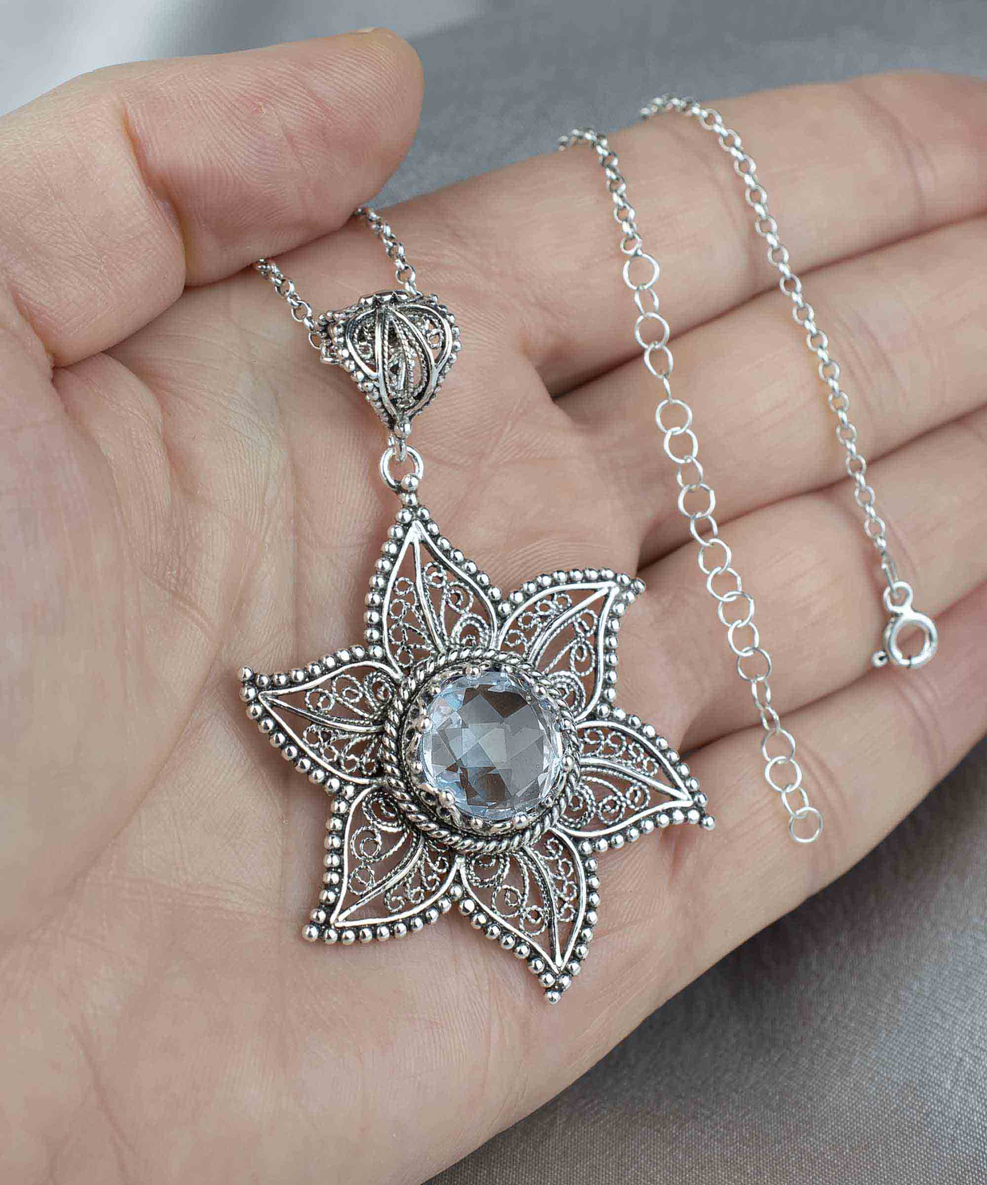 Handcrafted silver pendant featuring intricate filigree art and a blue quartz gemstone, showcasing elegance and sophistication.