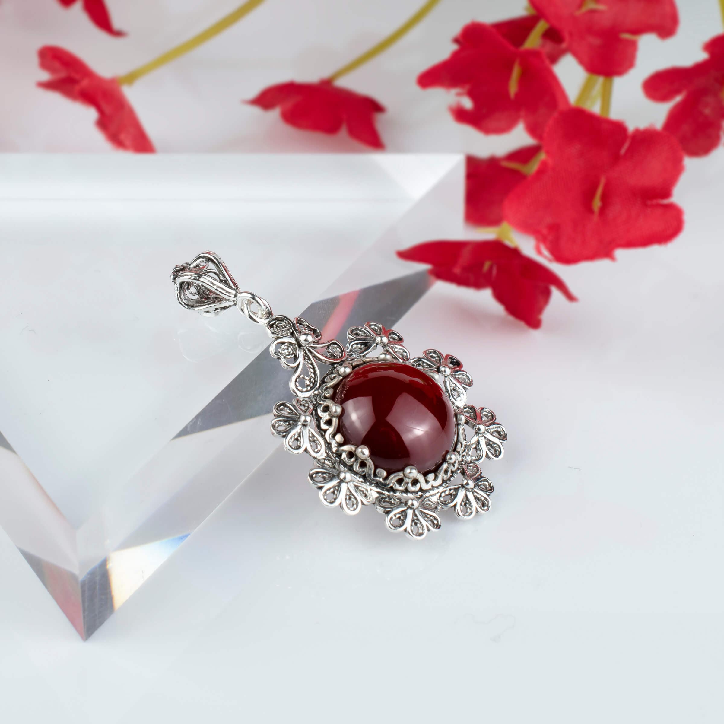 Sterling silver filigree pendant featuring a round cut carnelian gemstone in a floral design, showcasing intricate metalwork.