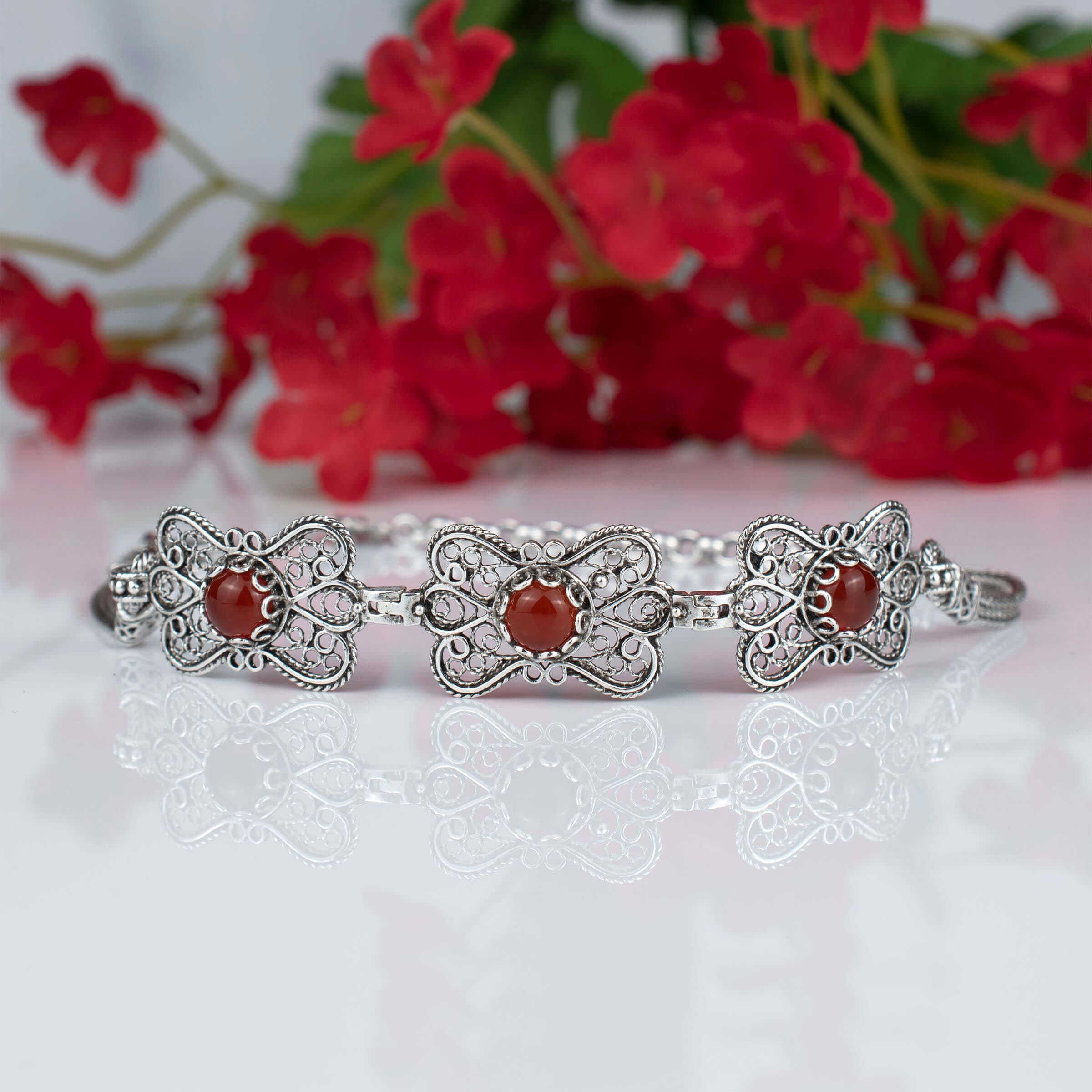 Elegant silver link bracelet featuring a butterfly design and a natural Carnelian gemstone, showcasing intricate filigree art.