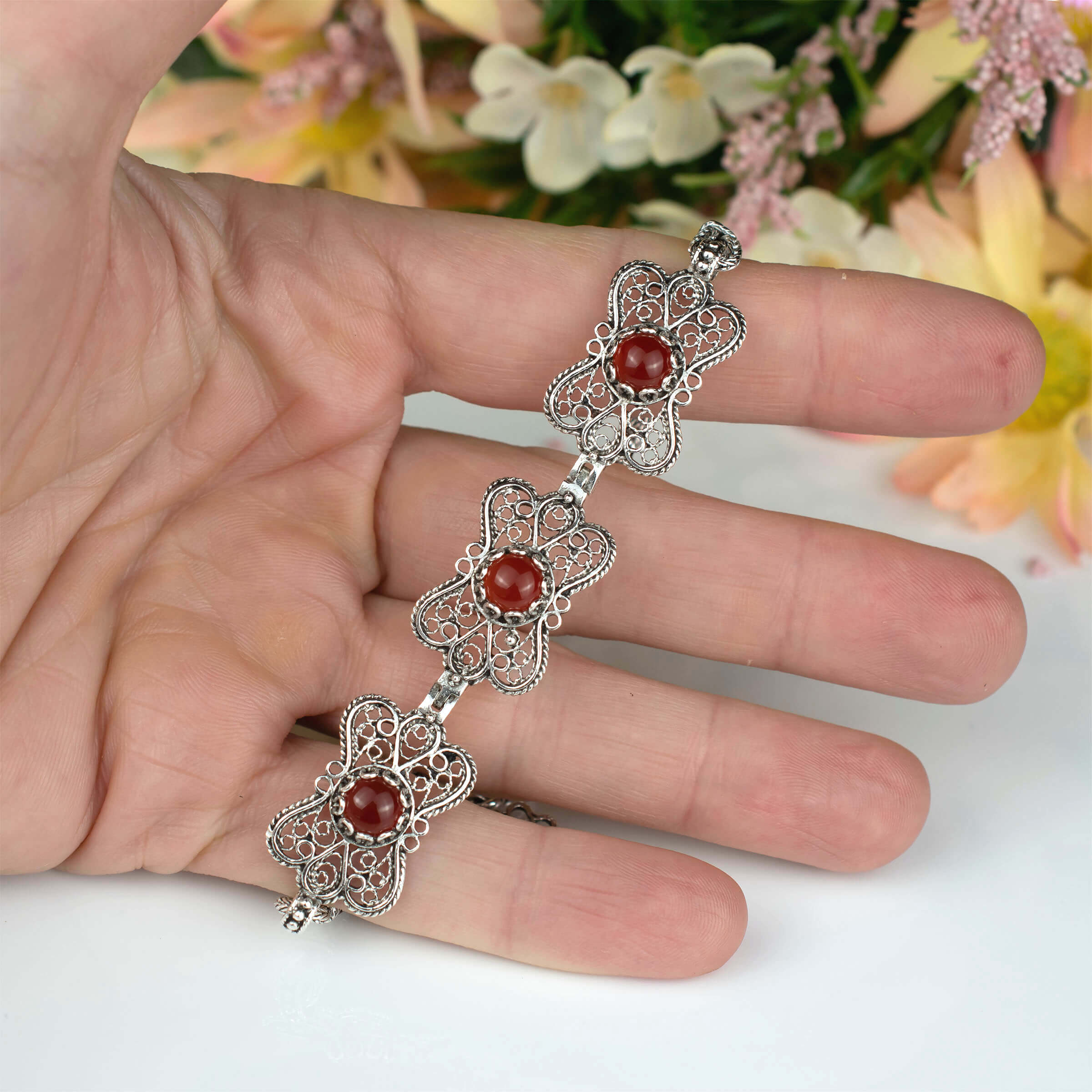 Elegant silver link bracelet featuring a butterfly design and a natural Carnelian gemstone, showcasing intricate filigree art.