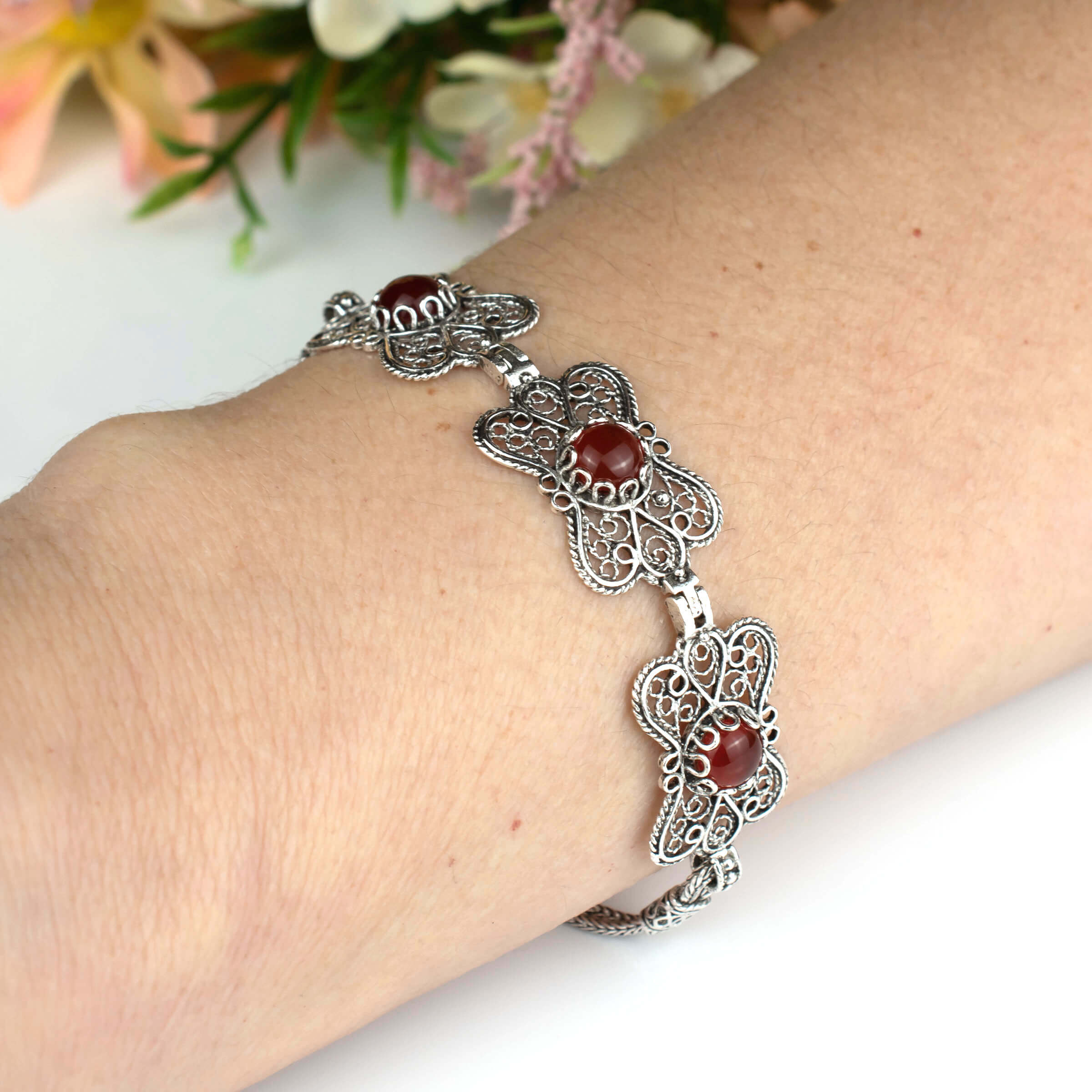 Elegant silver link bracelet featuring a butterfly design and a natural Carnelian gemstone, showcasing intricate filigree art.