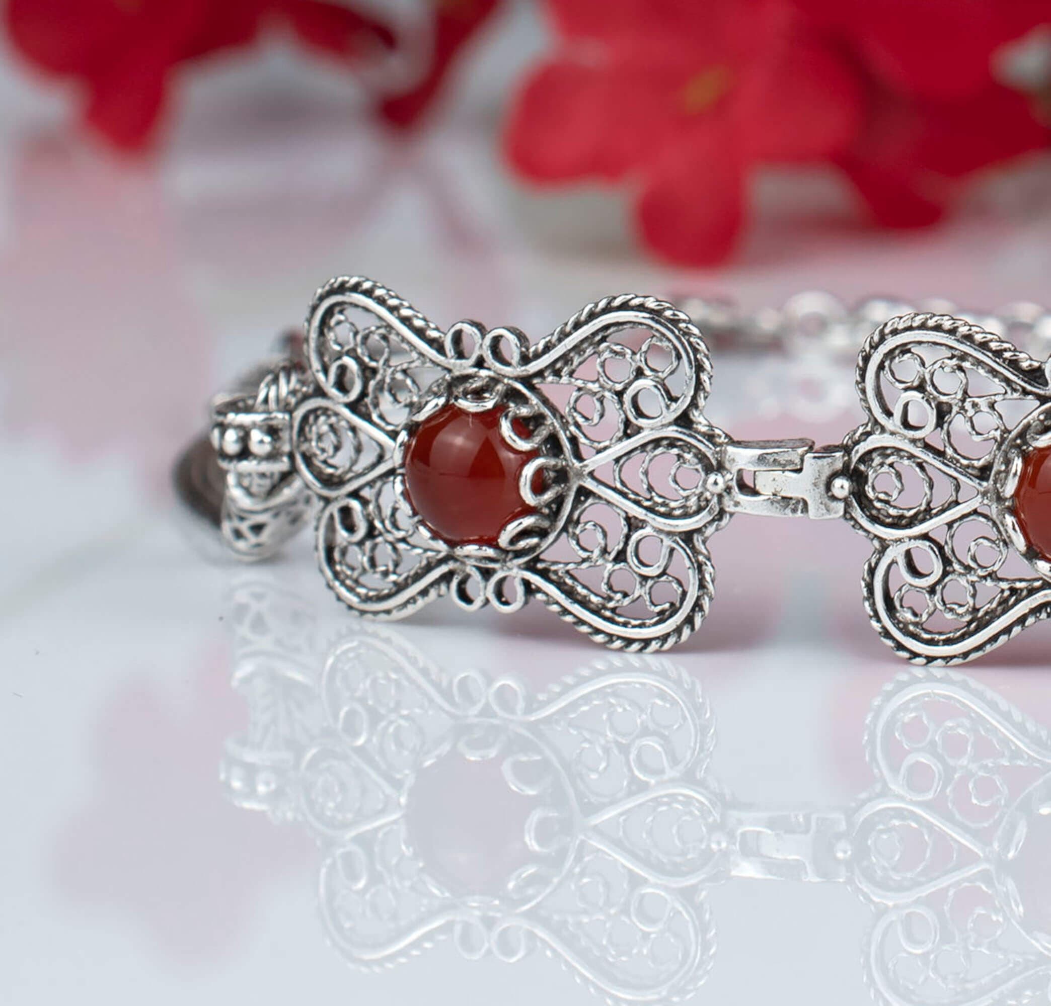 Elegant silver link bracelet featuring a butterfly design and a natural Carnelian gemstone, showcasing intricate filigree art.