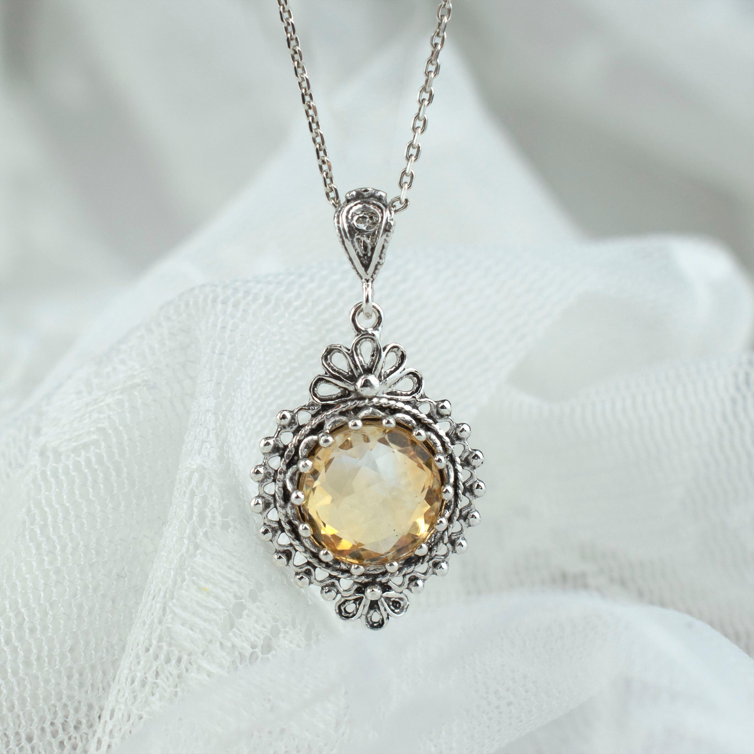 Elegant silver boho pendant necklace featuring a filigree design and a round-cut citrine gemstone.