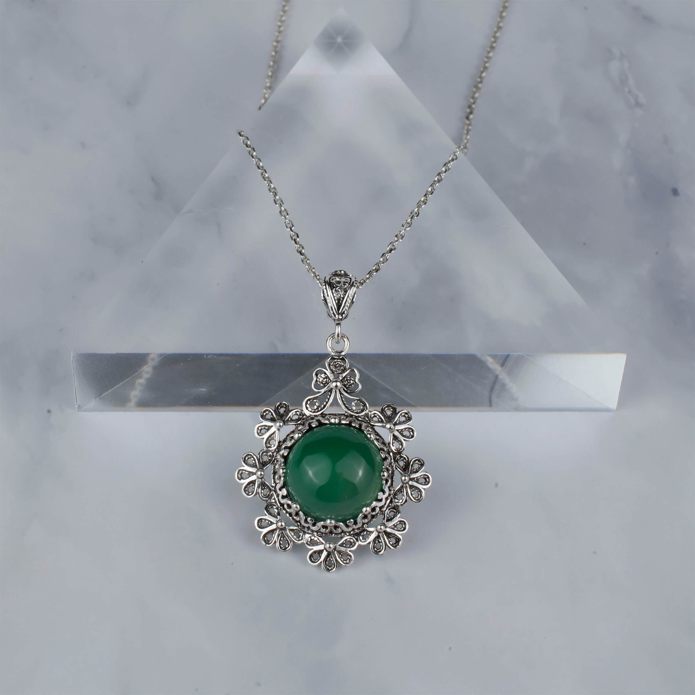 Sterling silver filigree pendant featuring a green agate gemstone in a floral design, showcasing intricate craftsmanship.