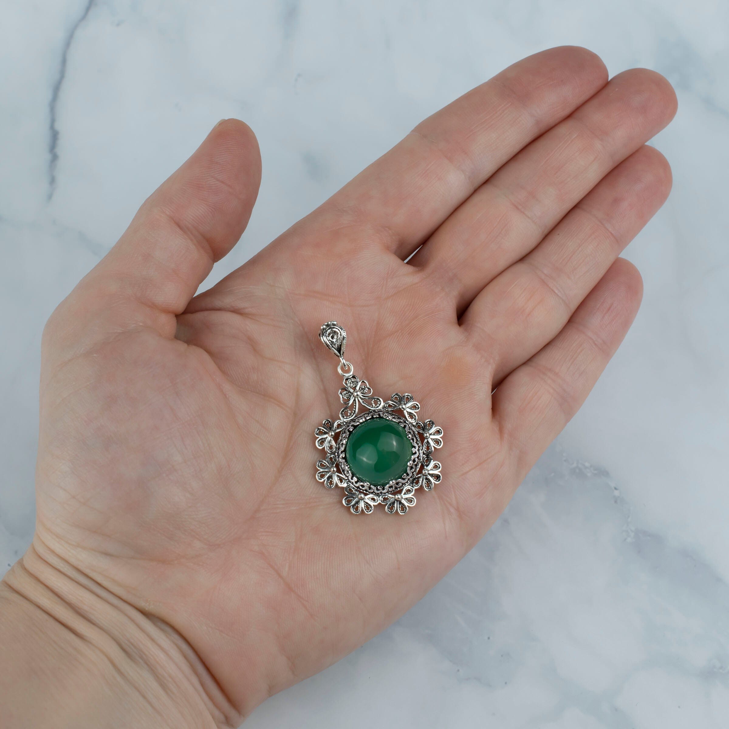 Sterling silver filigree pendant featuring a green agate gemstone in a floral design, showcasing intricate craftsmanship.