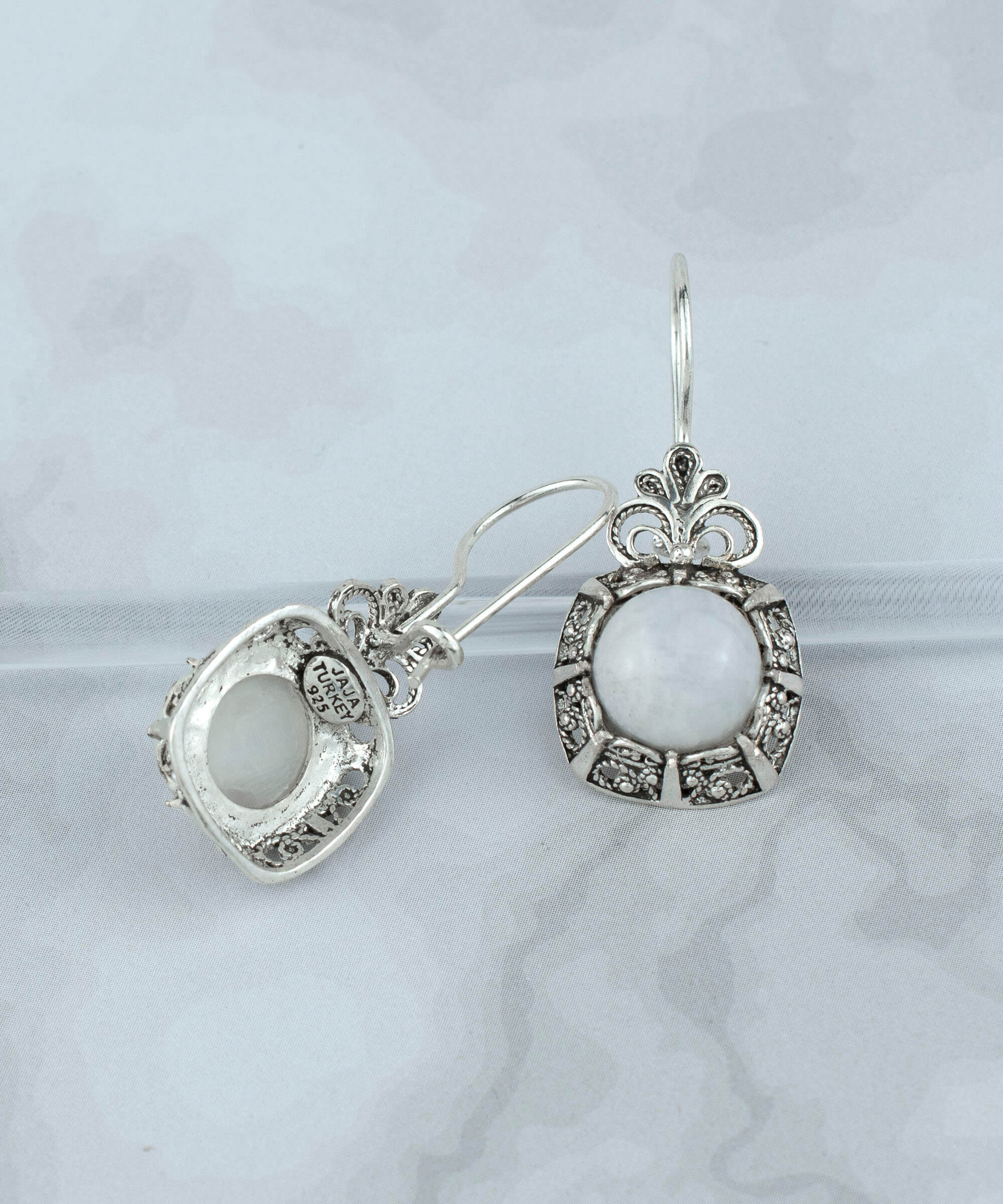 Elegant sterling silver drop earrings featuring a round-cut moonstone gemstone in a delicate filigree design.