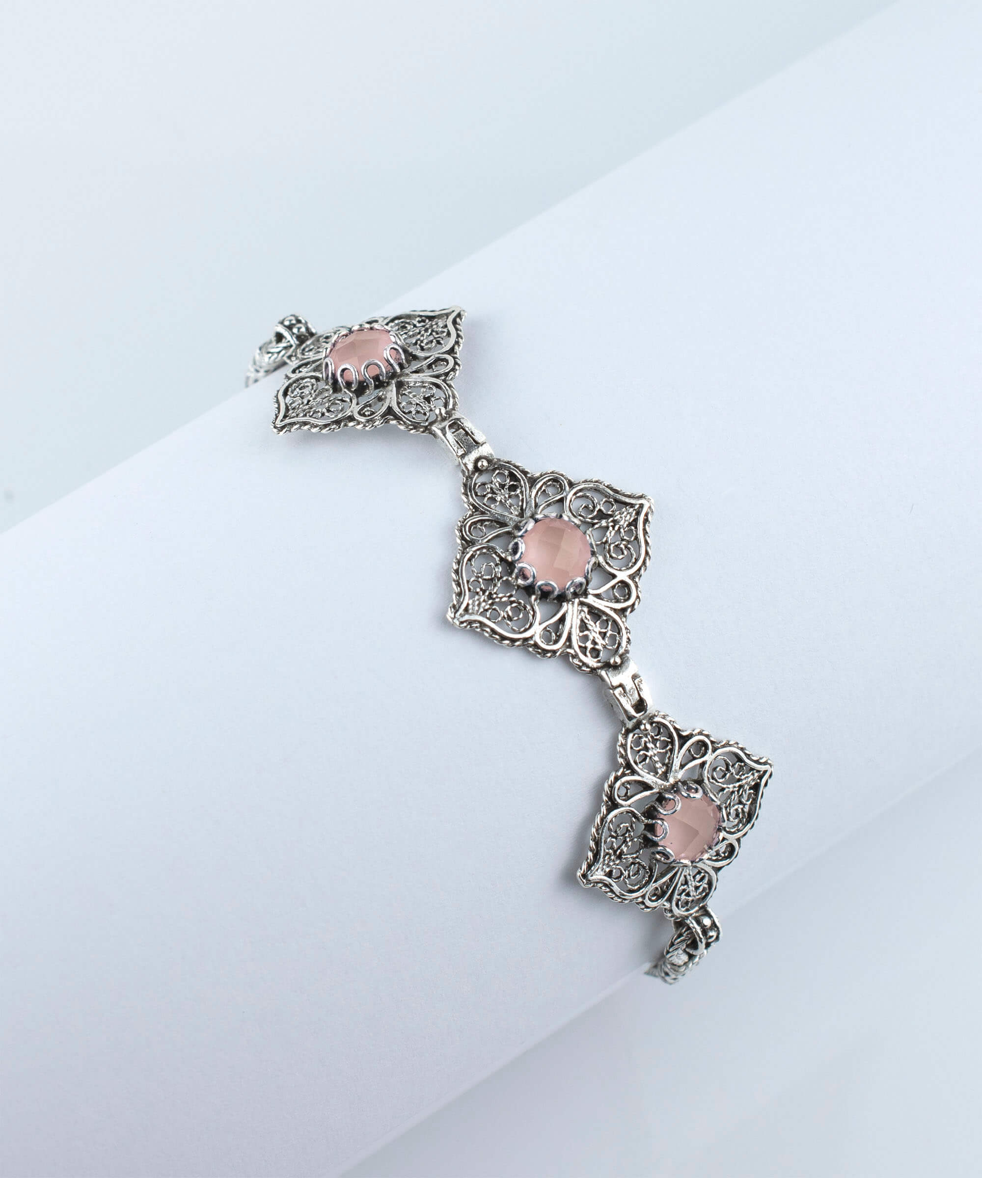 Elegant adjustable silver link bracelet featuring pink chalcedony gemstone in filigree art design.