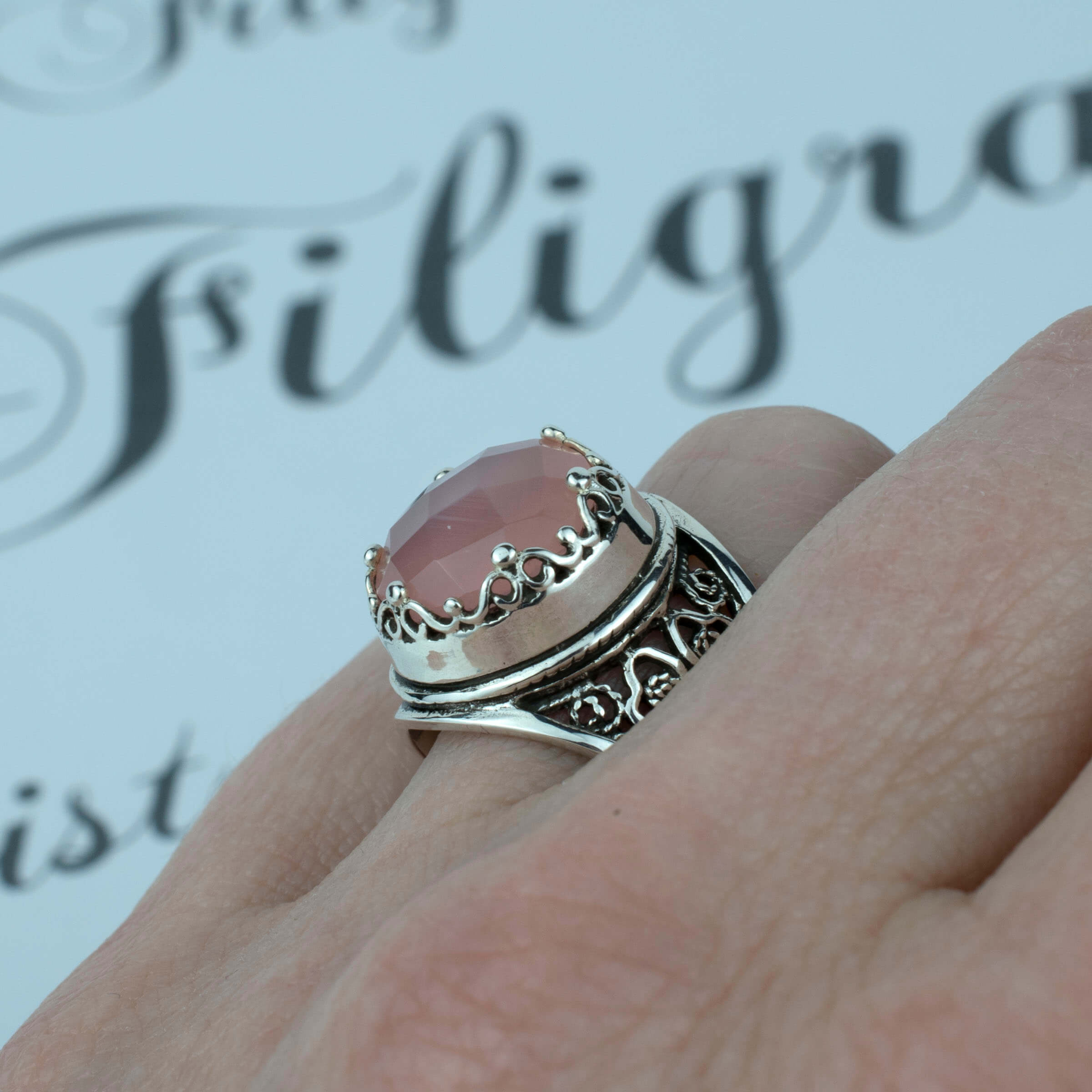 Sterling silver filigree art ring featuring a pink chalcedony gemstone, elegantly designed with intricate patterns.
