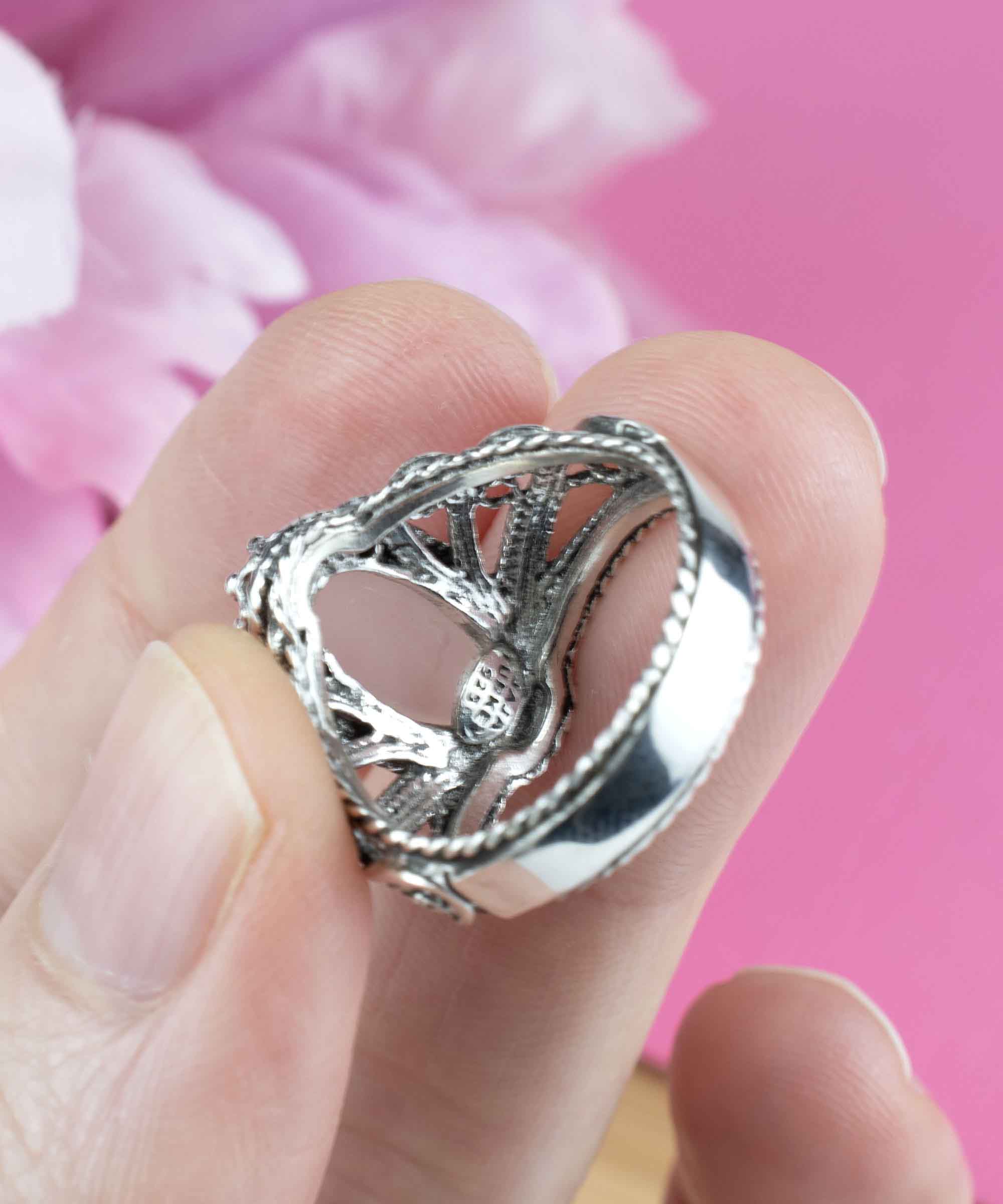 Elegant silver cocktail ring featuring intricate filigree design and a rose quartz gemstone in angel wings setting.