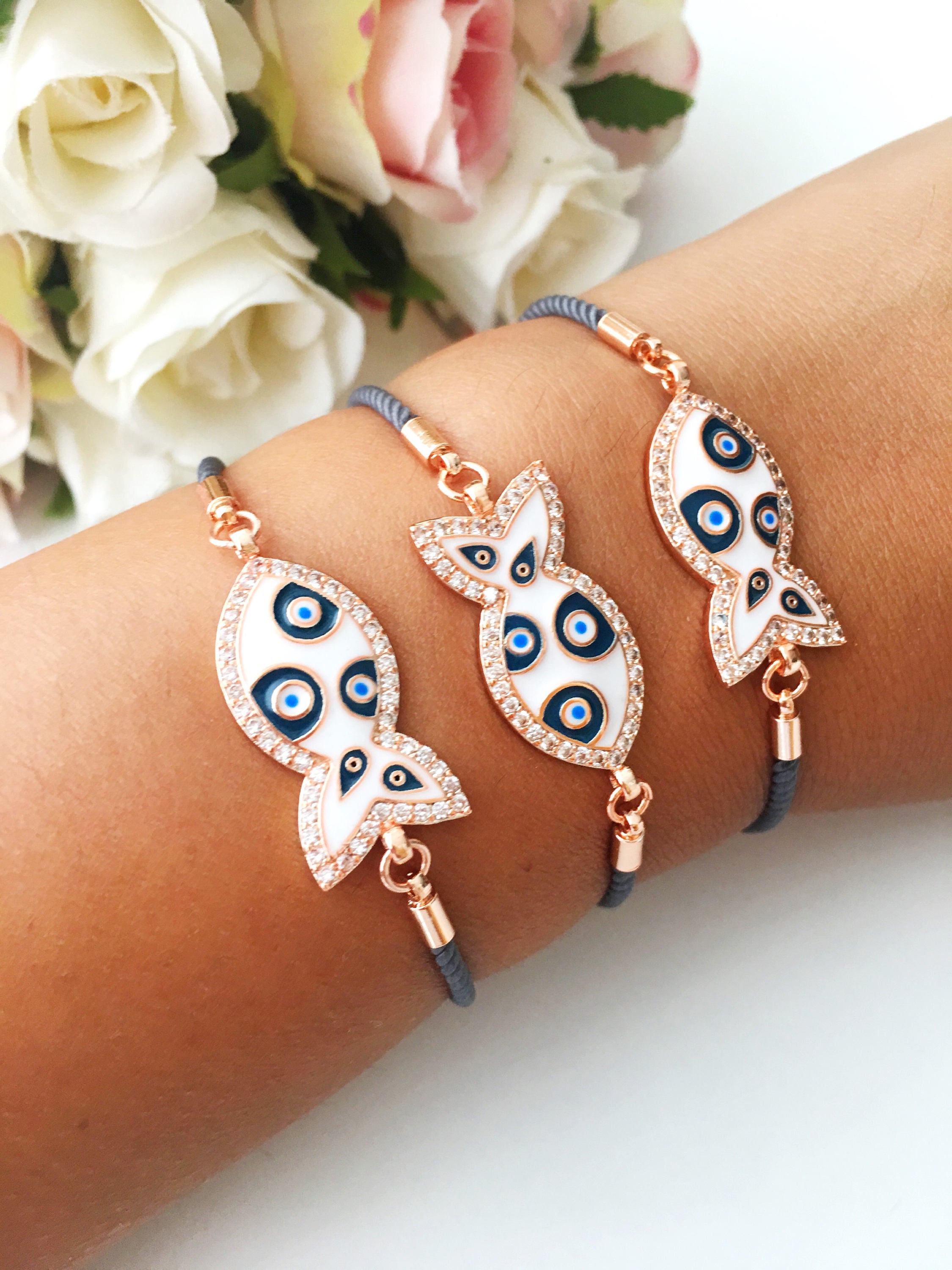 A stylish Fish Charm Bracelet featuring a rose gold plated evil eye charm on an adjustable string, perfect for everyday wear.