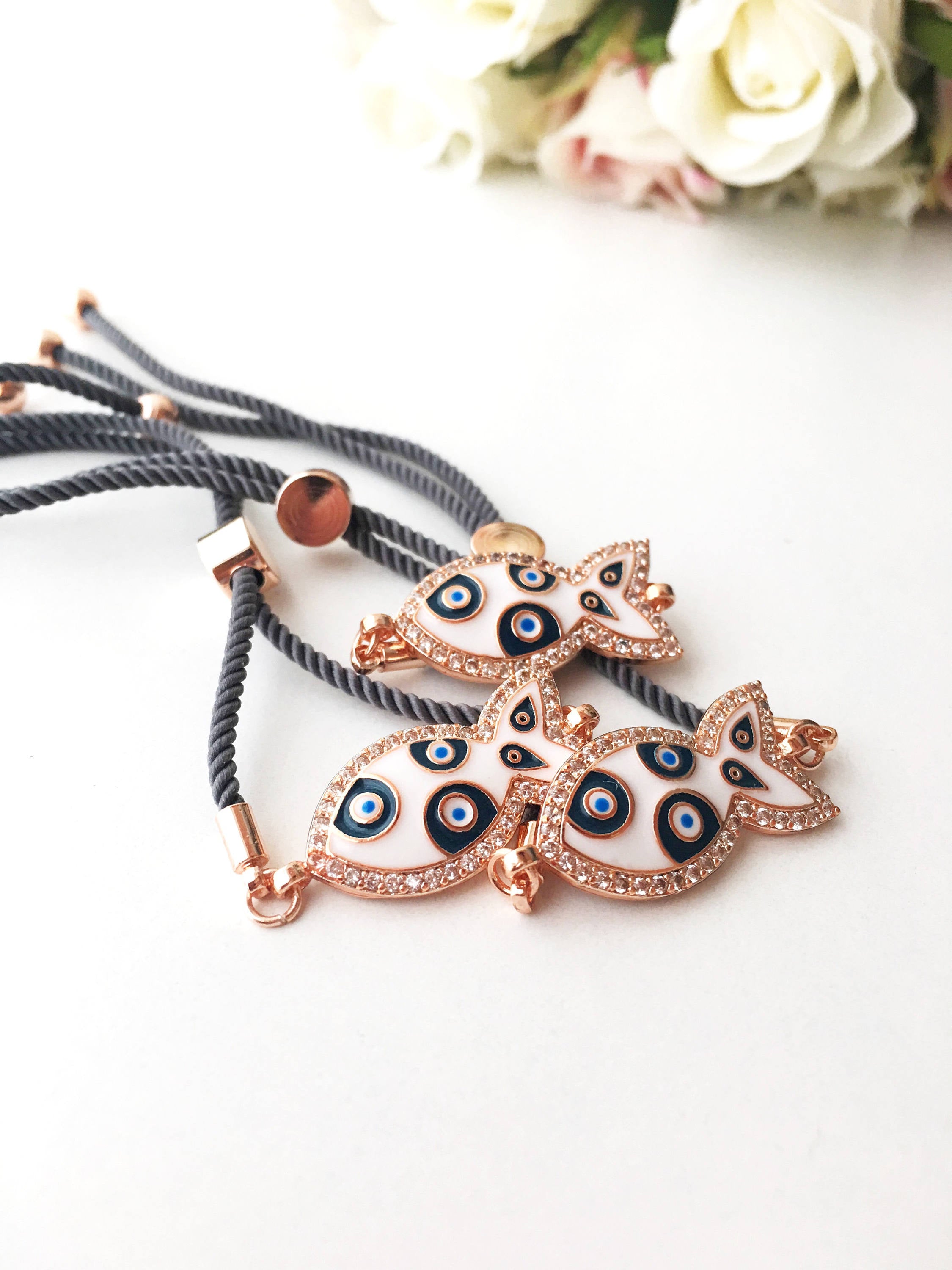 A stylish Fish Charm Bracelet featuring a rose gold plated evil eye charm on an adjustable string, perfect for everyday wear.