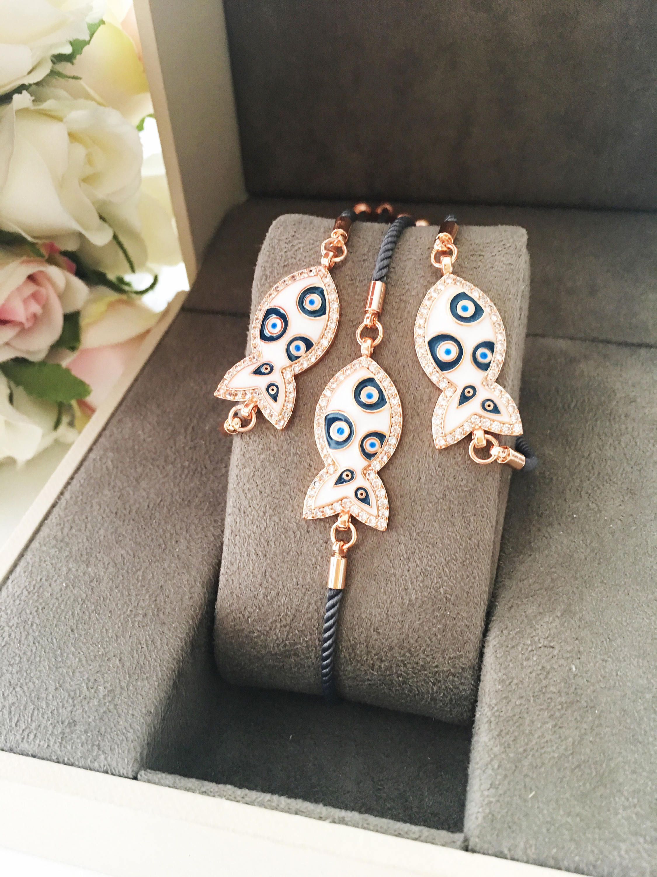 A stylish Fish Charm Bracelet featuring a rose gold plated evil eye charm on an adjustable string, perfect for everyday wear.