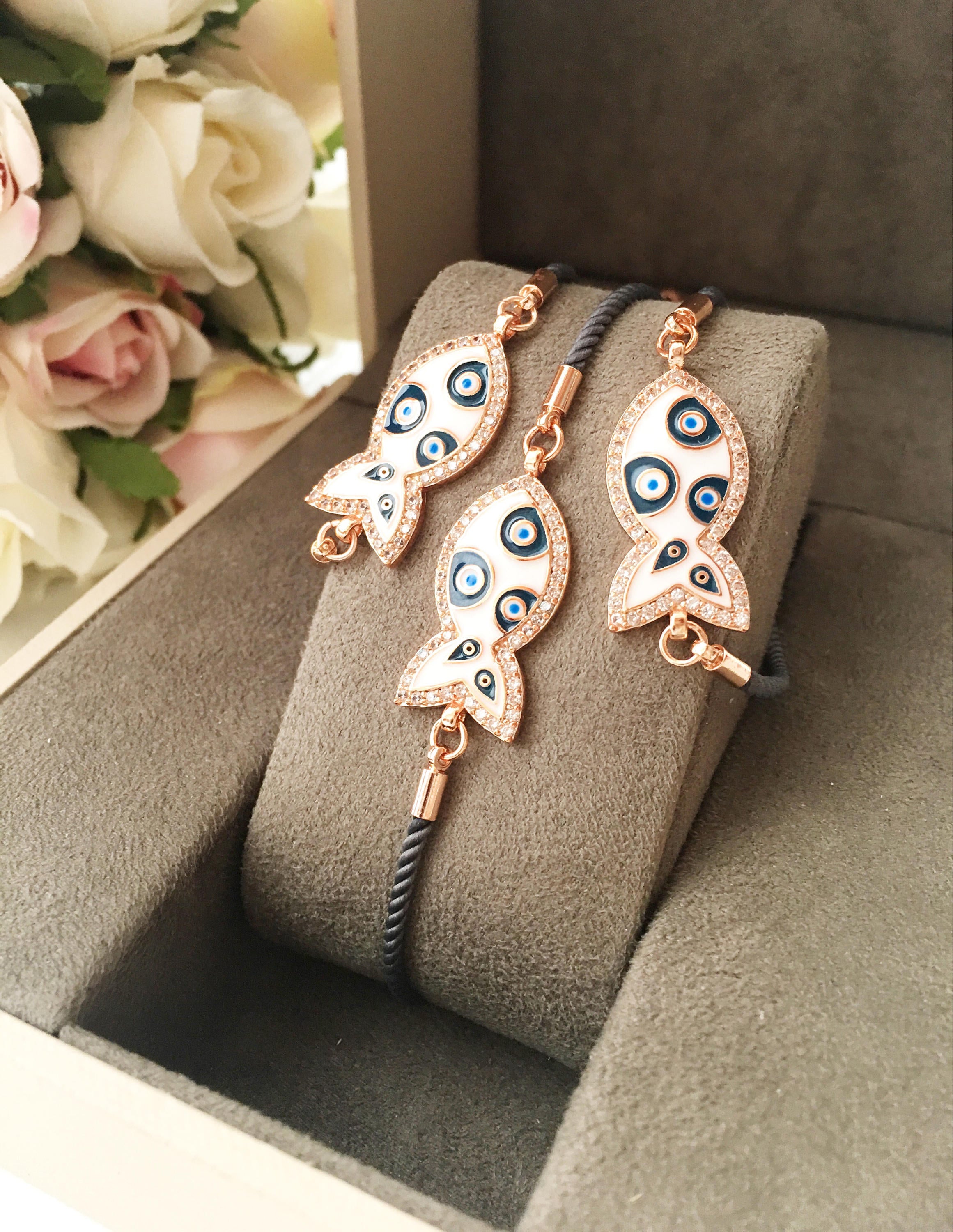 A stylish Fish Charm Bracelet featuring a rose gold plated evil eye charm on an adjustable string, perfect for everyday wear.