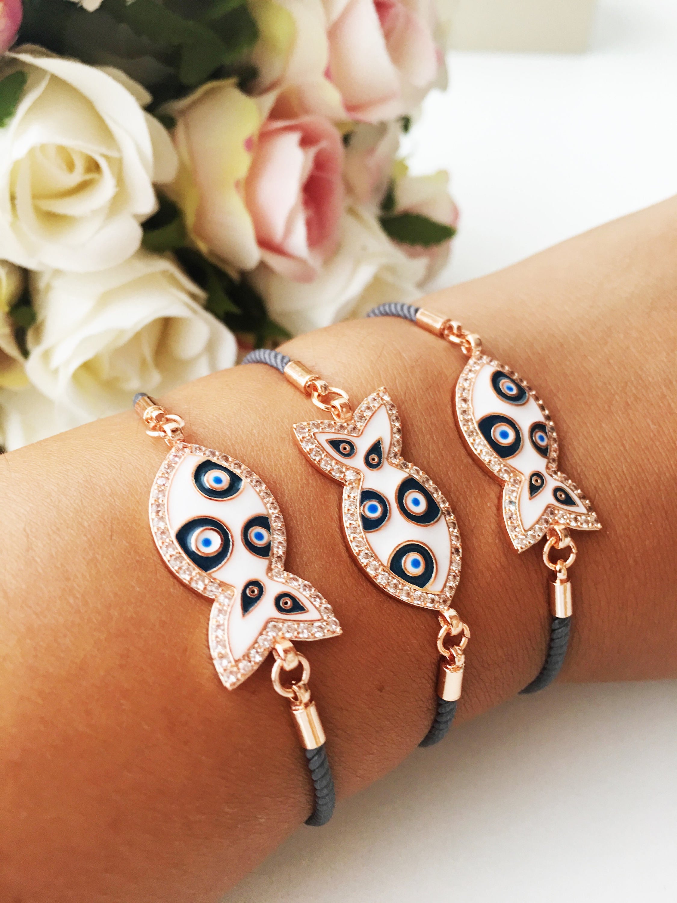 A stylish Fish Charm Bracelet featuring a rose gold plated evil eye charm on an adjustable string, perfect for everyday wear.